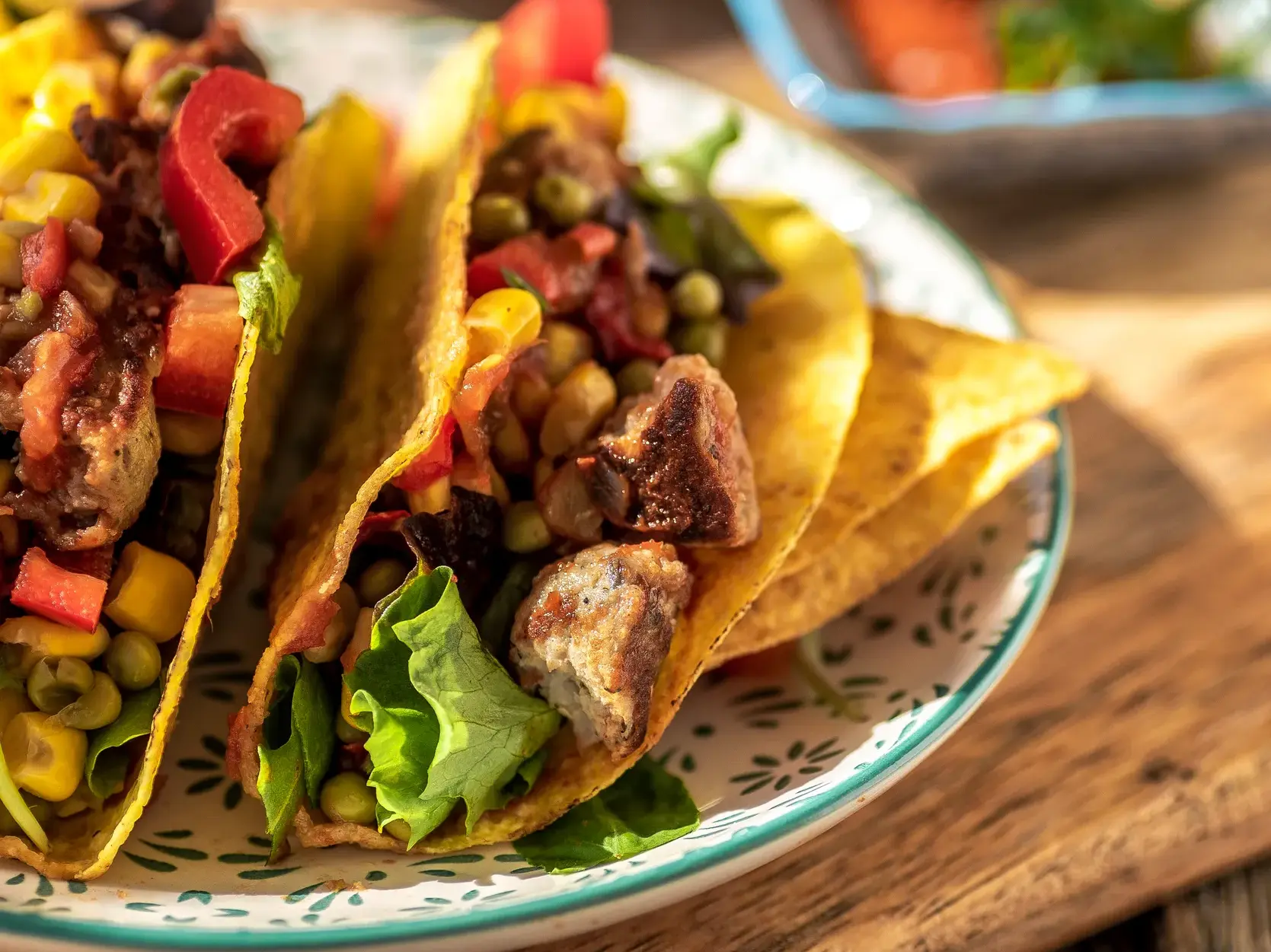 Nahaufnahme von zwei mexikanischen Tacos, gefüllt mit Fleisch, Mais und Paprika, serviert auf einer Streetfood-Tour.