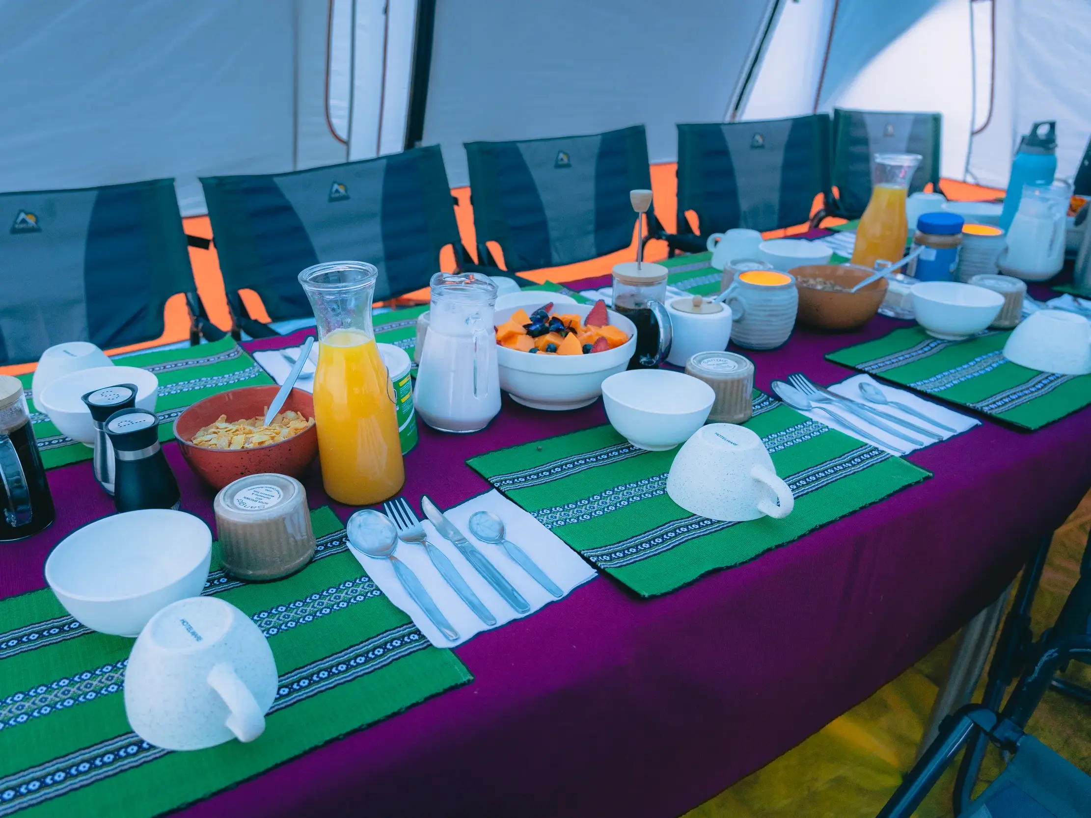 Gedeckter Frühstückstisch im Luxuszelt mit frischem Obst, Müsli und Saft während einer Trekkingreise in der Cordillera Blanca.