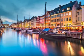 Stimmungsvolle Abenddämmerung am Nyhavn in Kopenhagen mit bunten Giebelhäusern und Cafés, die sich im Kanal spiegeln.