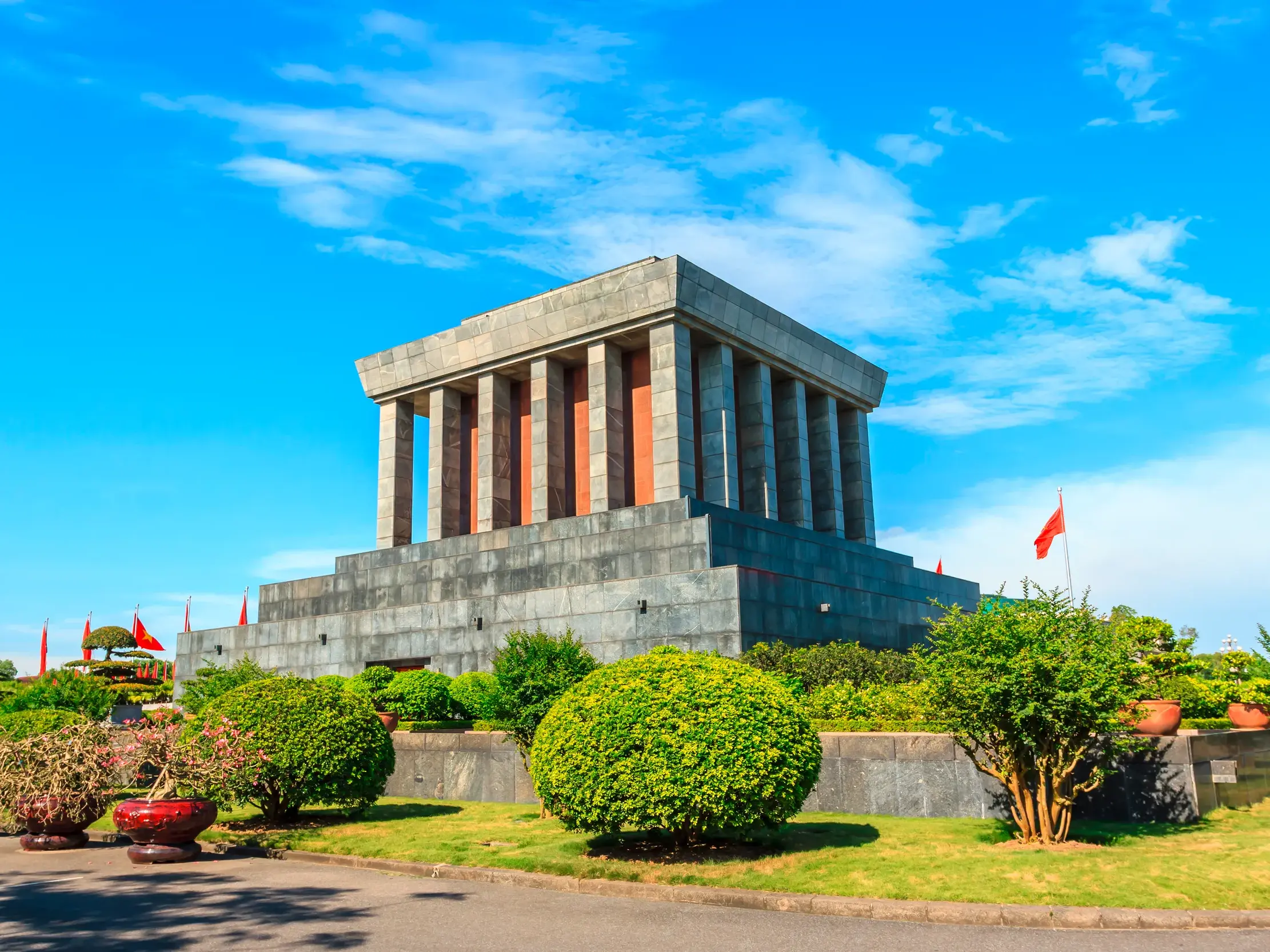 Das imposante Ho-Chi-Minh-Mausoleum in Hanoi, umgeben von einer grünen Parkanlage an einem sonnigen Tag.