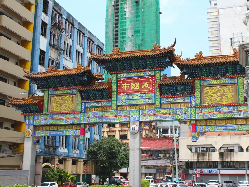 Das prächtige, bunte Chinatown Friendship Arch in Binondo, Manila, vor der Kulisse urbaner Hochhäuser bei Tag.