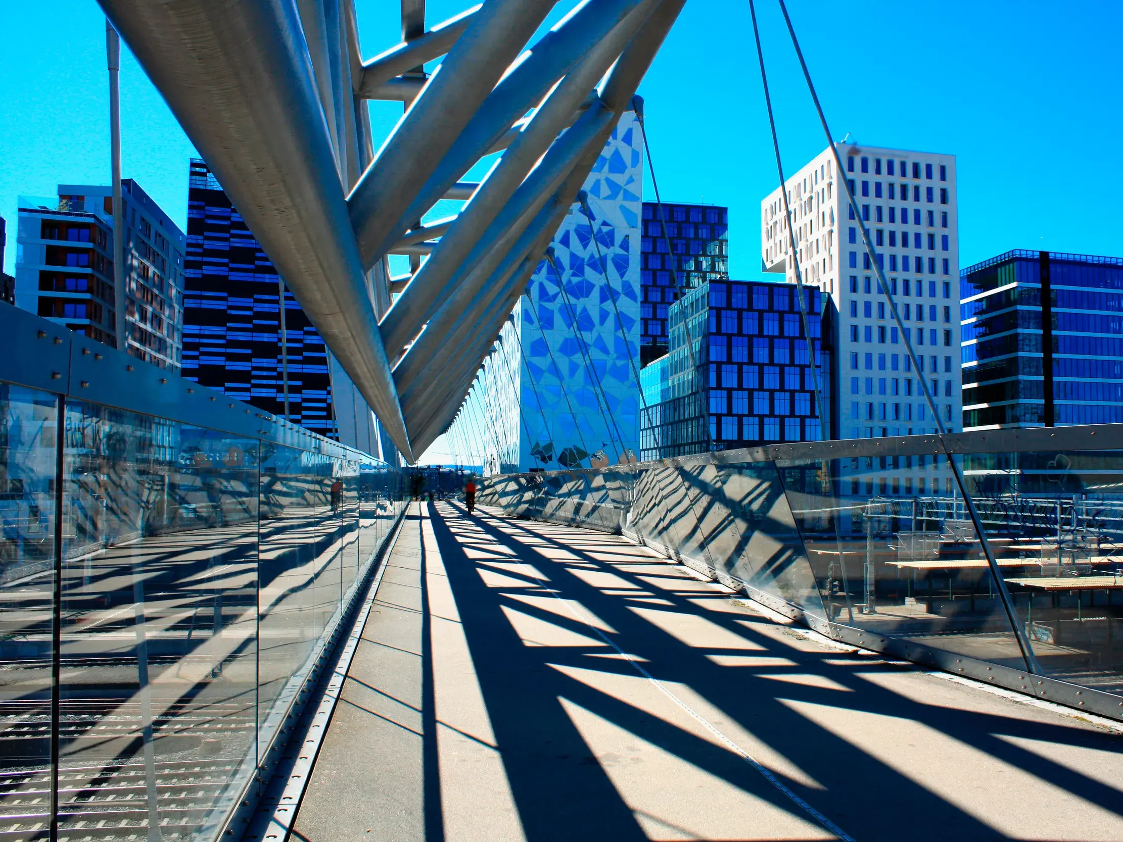 Sonnige Ansicht der modernen Akrobaten-Brücke im Viertel Björvika mit Blick auf die Barcode-Hochhäuser in Oslo.