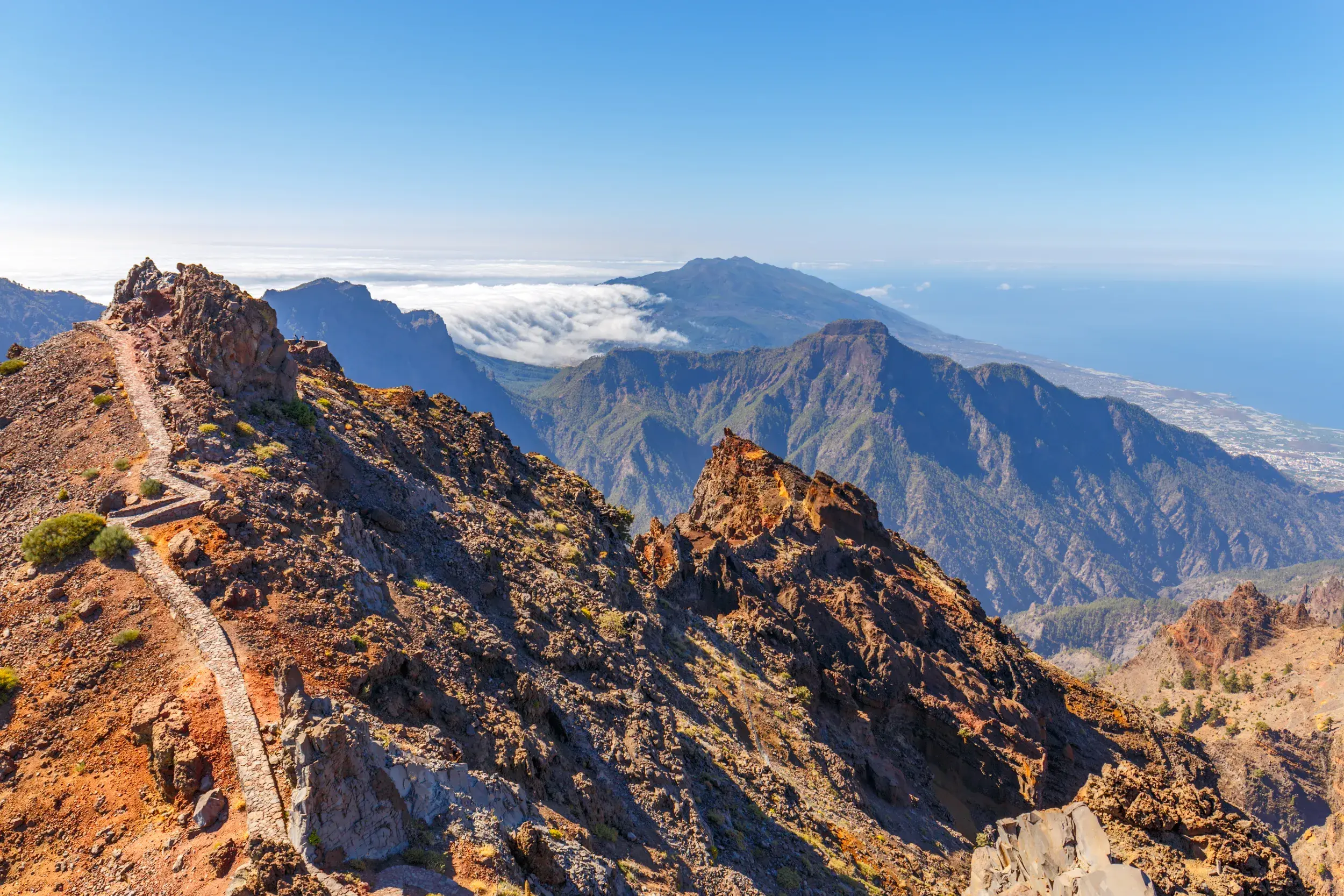 Schmaler Wanderpfad auf dem Grat des Roque de los Muchachos mit Panoramablick über die Caldera de Taburiente auf La Palma.
