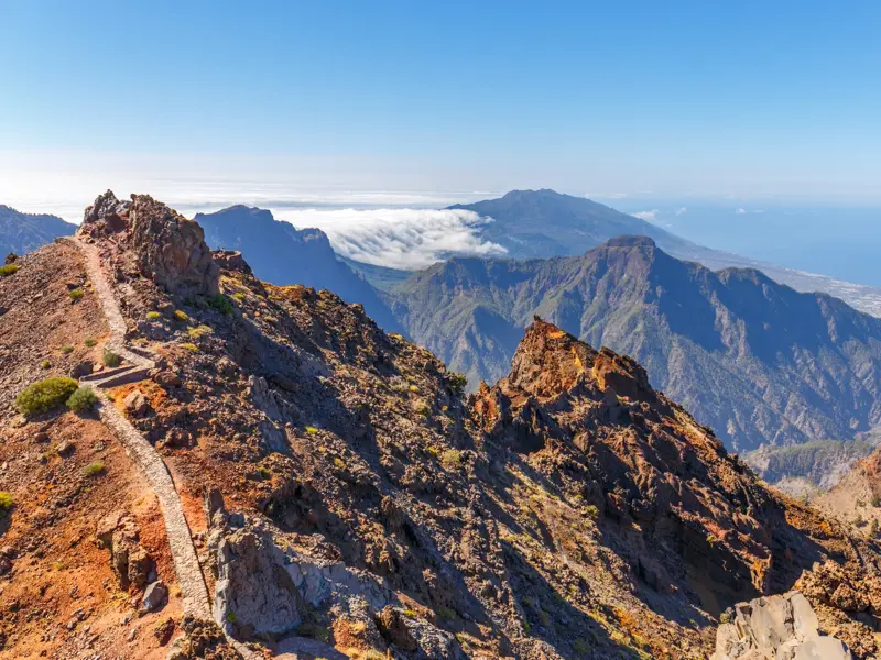 Schmaler Wanderpfad auf dem Grat des Roque de los Muchachos mit Panoramablick über die Caldera de Taburiente auf La Palma.