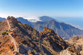 Schmaler Wanderpfad auf dem Grat des Roque de los Muchachos mit Panoramablick über die Caldera de Taburiente auf La Palma.