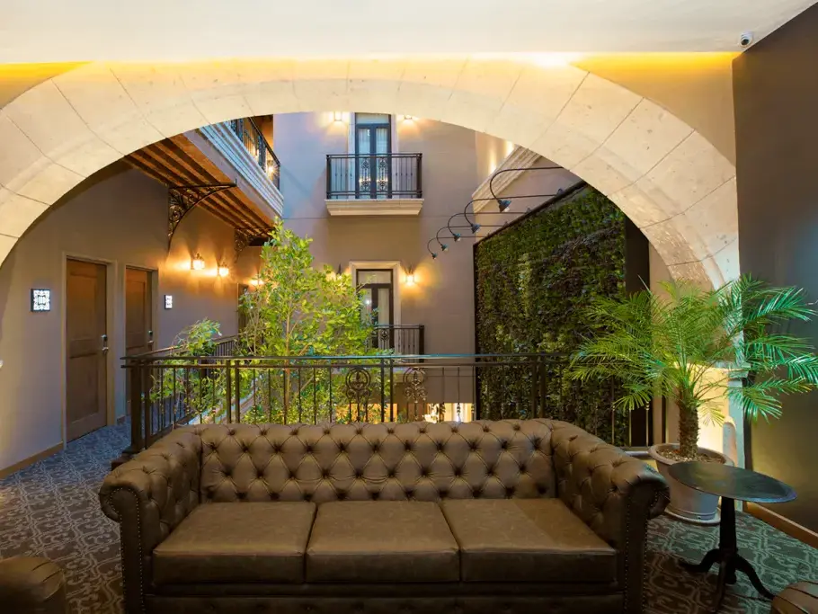 Stilvolle Lounge mit Ledersofa im Hotel Histórico Central, gerahmter Blick durch einen Torbogen auf den kolonialen Innenhof.