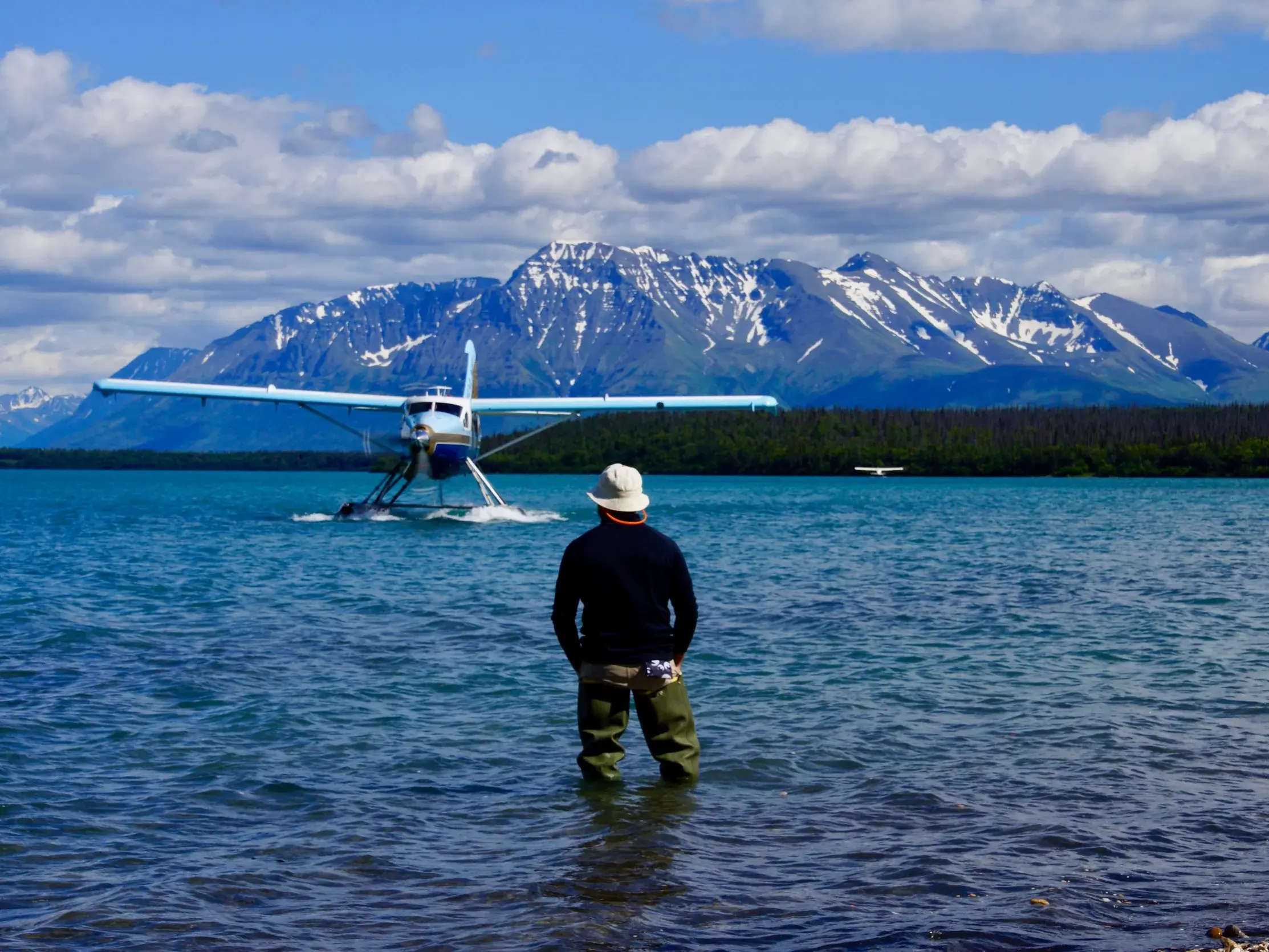Ein Reisender wartet am Ufer eines Sees in Alaska auf den Start eines Buschflugzeugs zur Bärenbeobachtung.