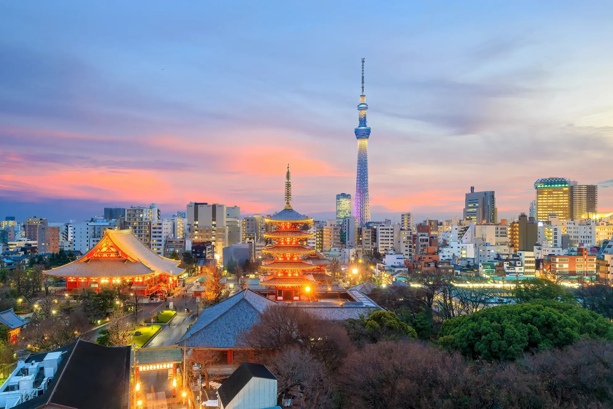Der beleuchtete Sensō-ji Tempel und die Pagode vor der modernen Skyline Tokios mit dem Tokyo Skytree bei Sonnenuntergang.