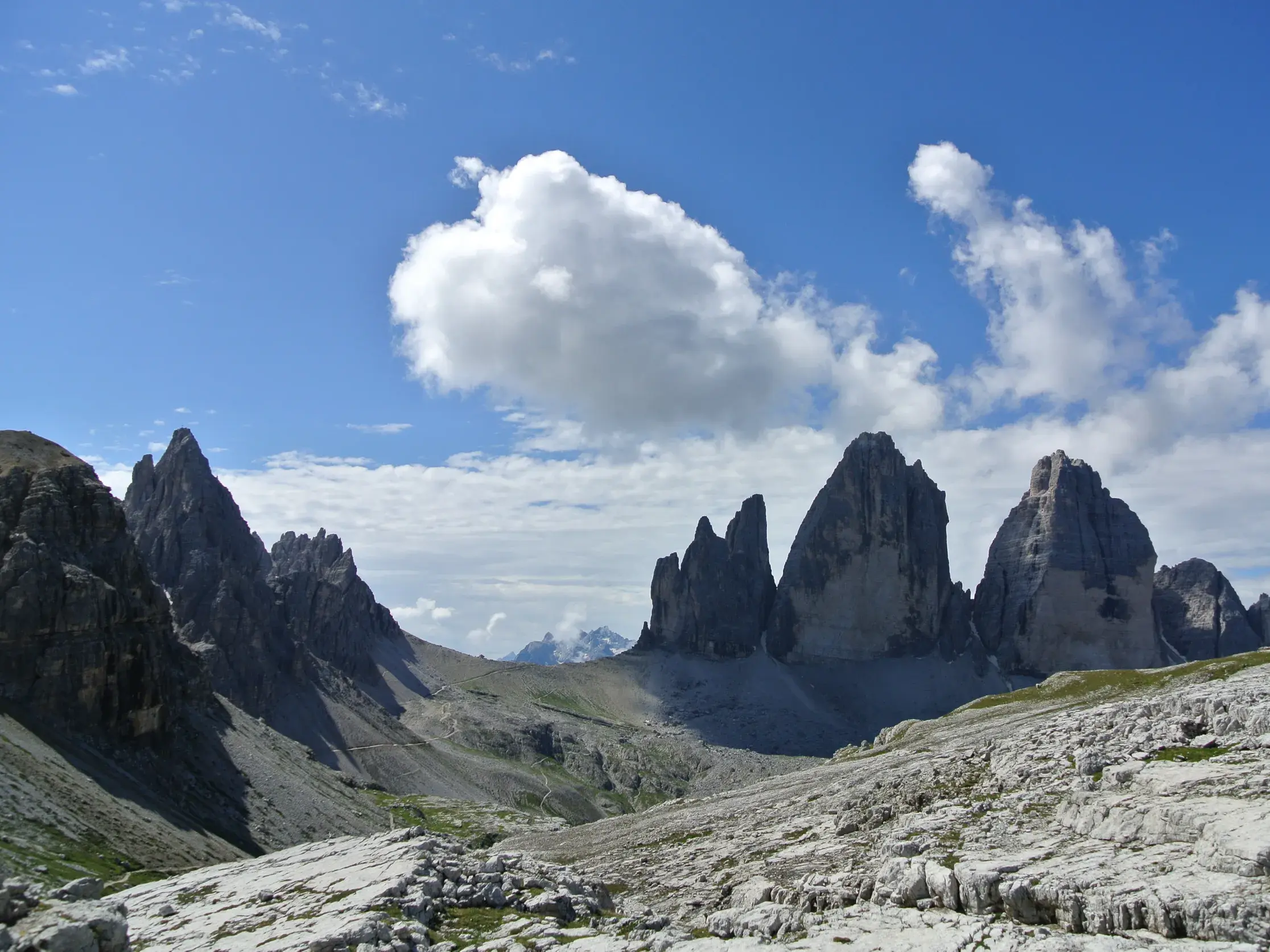 Blick auf die Drei Zinnen im UNESCO Welterbe der Dolomiten während der Hauser Alpenüberquerung über ein felsiges Karstplateau.