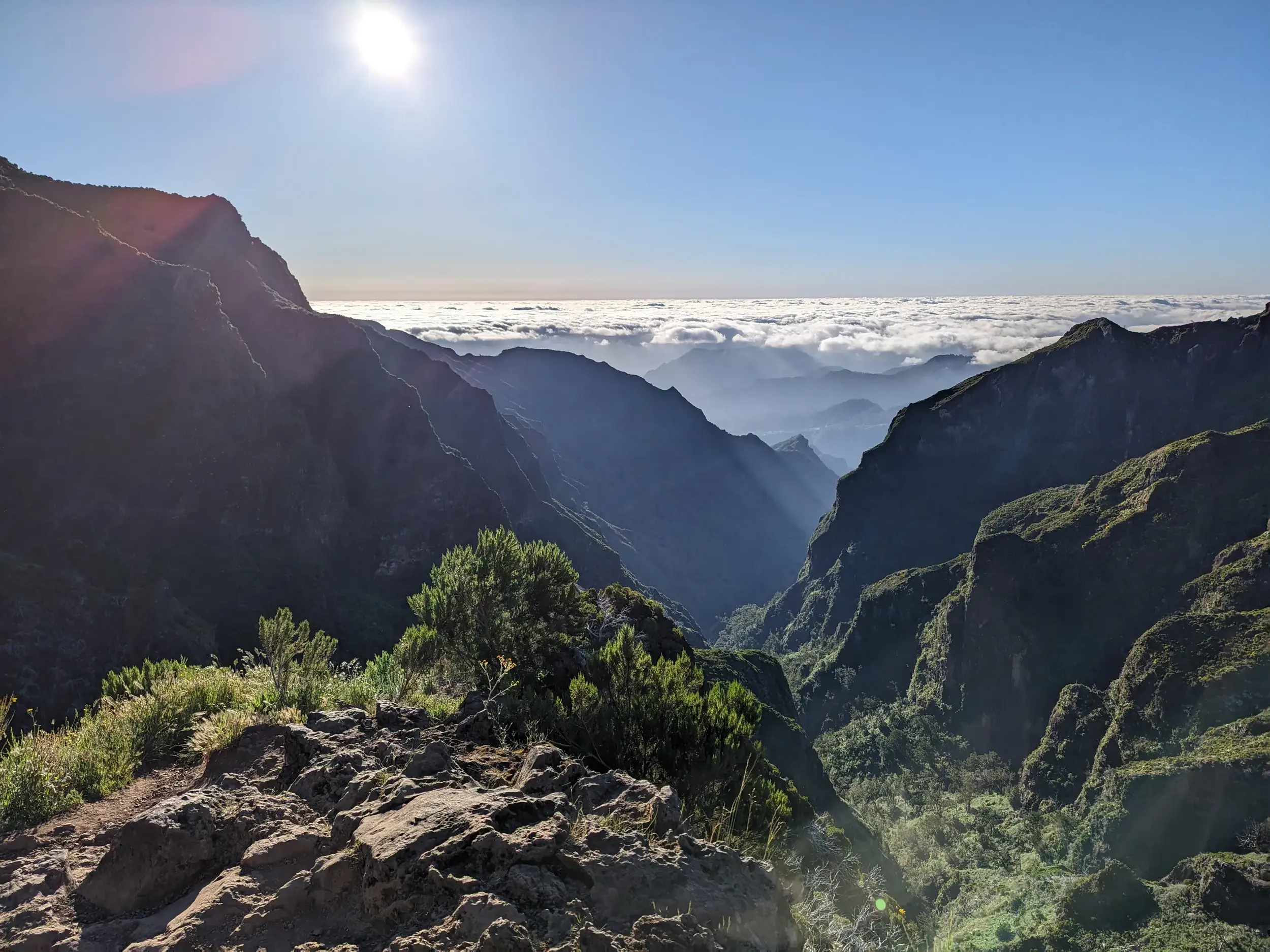Weitreichender Ausblick von einem Wanderweg am Pico do Arieiro auf Madeiras Bergwelt mit tiefen Tälern und einem Wolkenmeer.