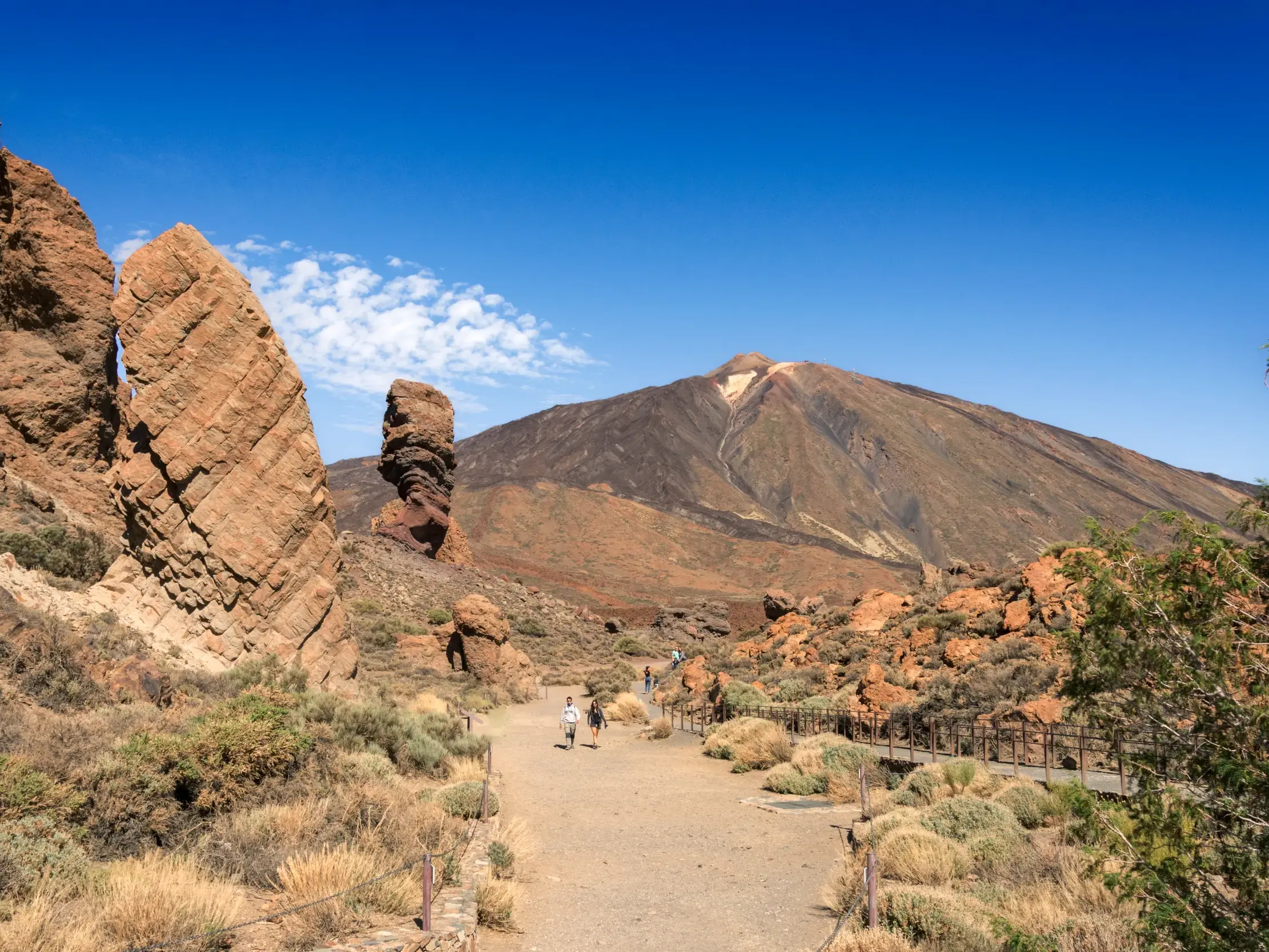 Wanderer einer Kleingruppe auf einem Pfad bei den Felsformationen Roques de García mit Blick auf den Vulkan Teide auf Teneriffa.