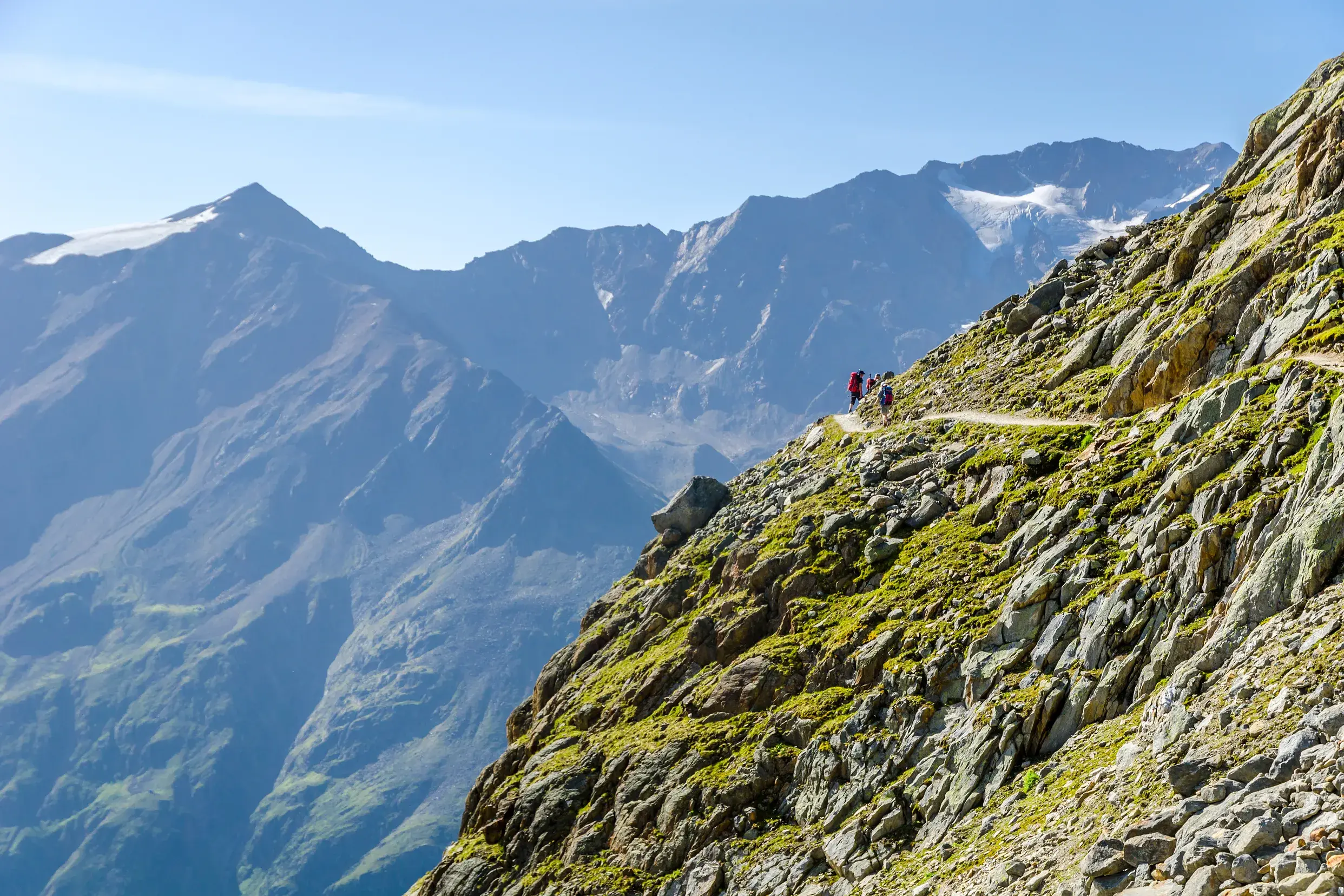 Kleine Wandergruppe auf dem Panoramahöhenweg zum Venter Tal mit Blick auf die Gletscher der Wildspitze in den Ötztaler Alpen.