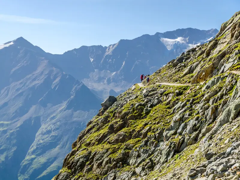 Kleine Wandergruppe auf dem Panoramahöhenweg zum Venter Tal mit Blick auf die Gletscher der Wildspitze in den Ötztaler Alpen.