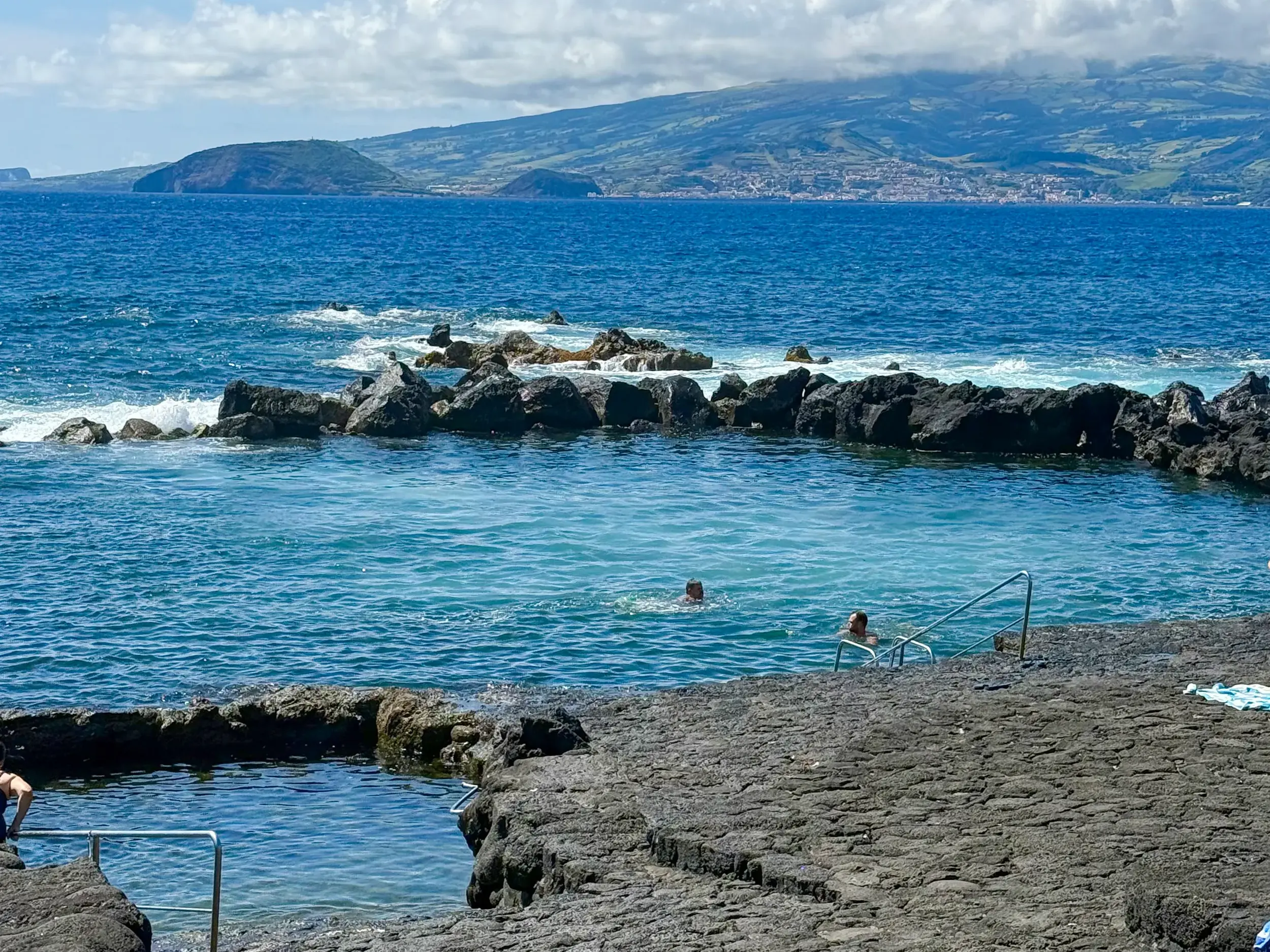 Entspanntes Baden in den Piscinas Naturais auf den Azoren, umgeben von schwarzen Lavafelsen mit Blick auf den weiten Atlantik.