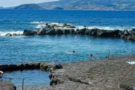 Entspanntes Baden in den Piscinas Naturais auf den Azoren, umgeben von schwarzen Lavafelsen mit Blick auf den weiten Atlantik.