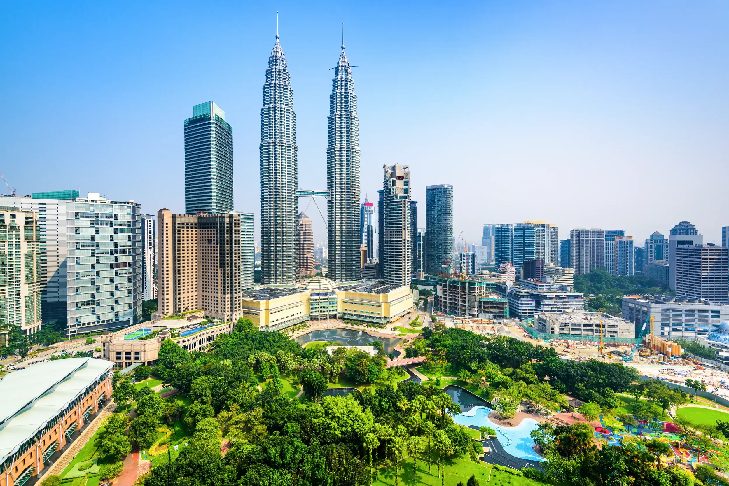 Die berühmten Petronas Twin Towers ragen im Zentrum der Skyline von Kuala Lumpur über den üppig grünen KLCC Park.