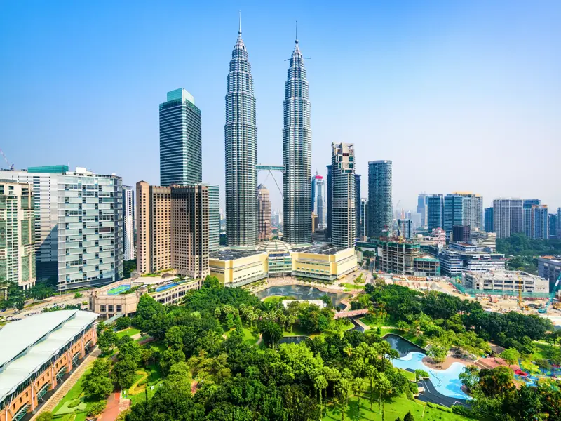 Die berühmten Petronas Twin Towers ragen im Zentrum der Skyline von Kuala Lumpur über den üppig grünen KLCC Park.