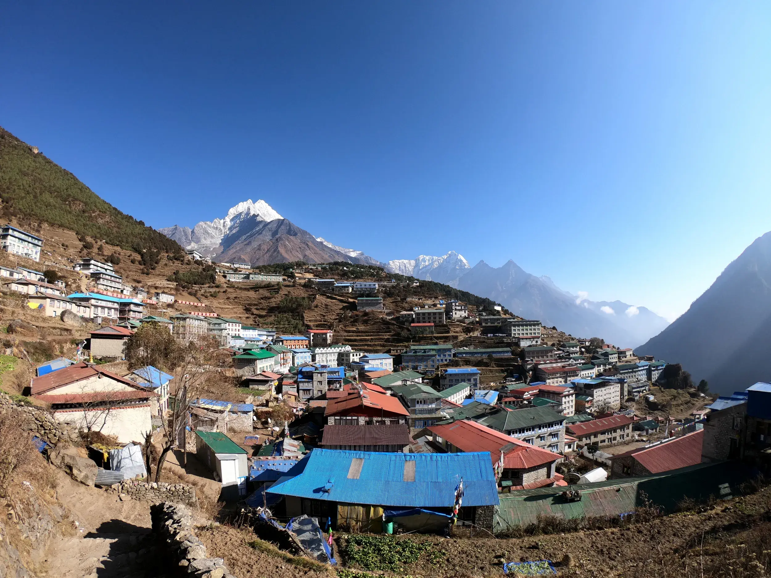 Panoramablick auf das Sherpa-Zentrum Namche Bazar mit bunten Dächern, gelegen an einem Hang in der Khumbu-Region Nepals.