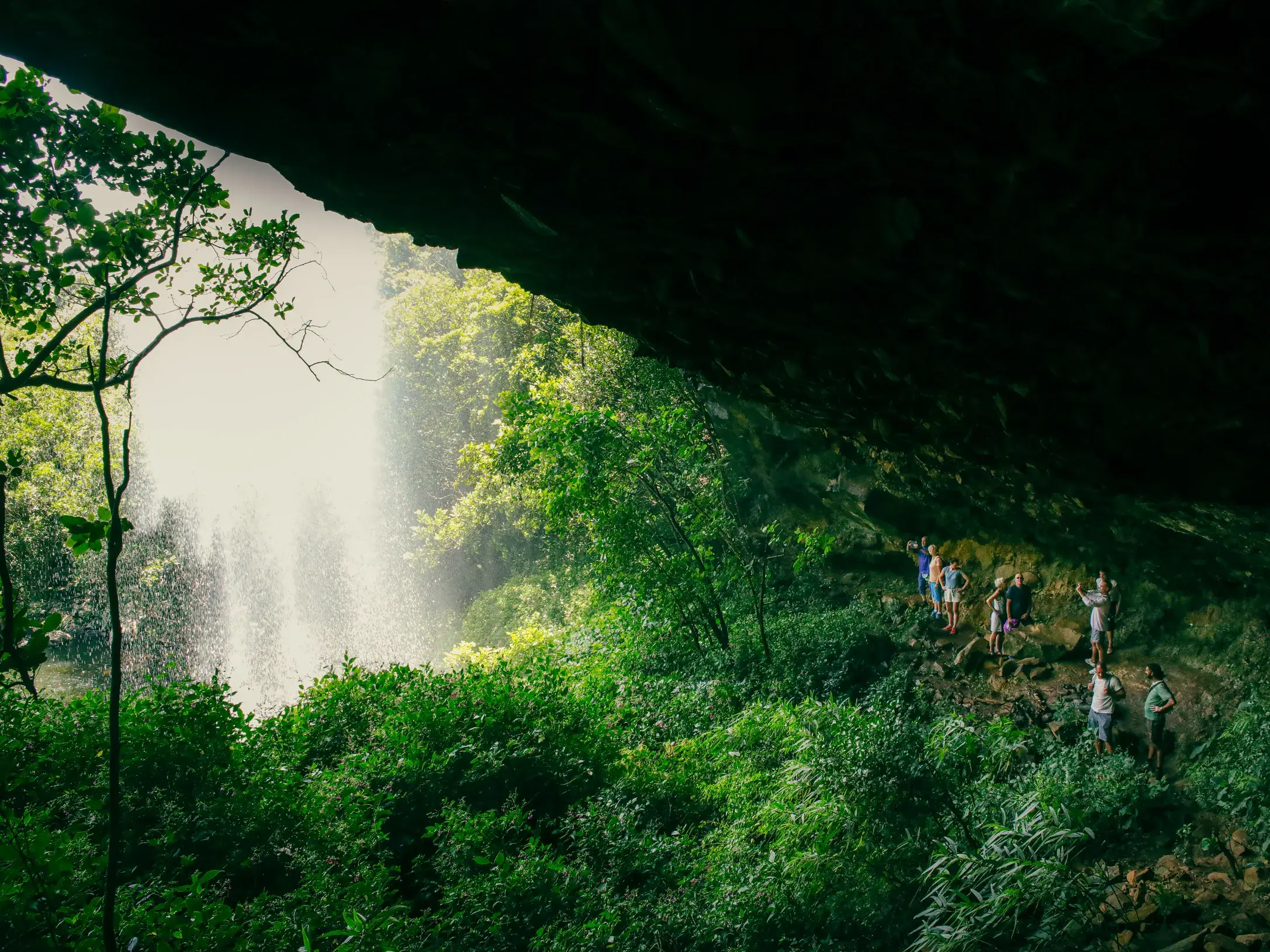 Eine Wandergruppe erkundet auf einem schmalen Pfad eine üppig grüne Schlucht mit Blick auf die tosenden Tamarind-Fälle auf Mauritius.