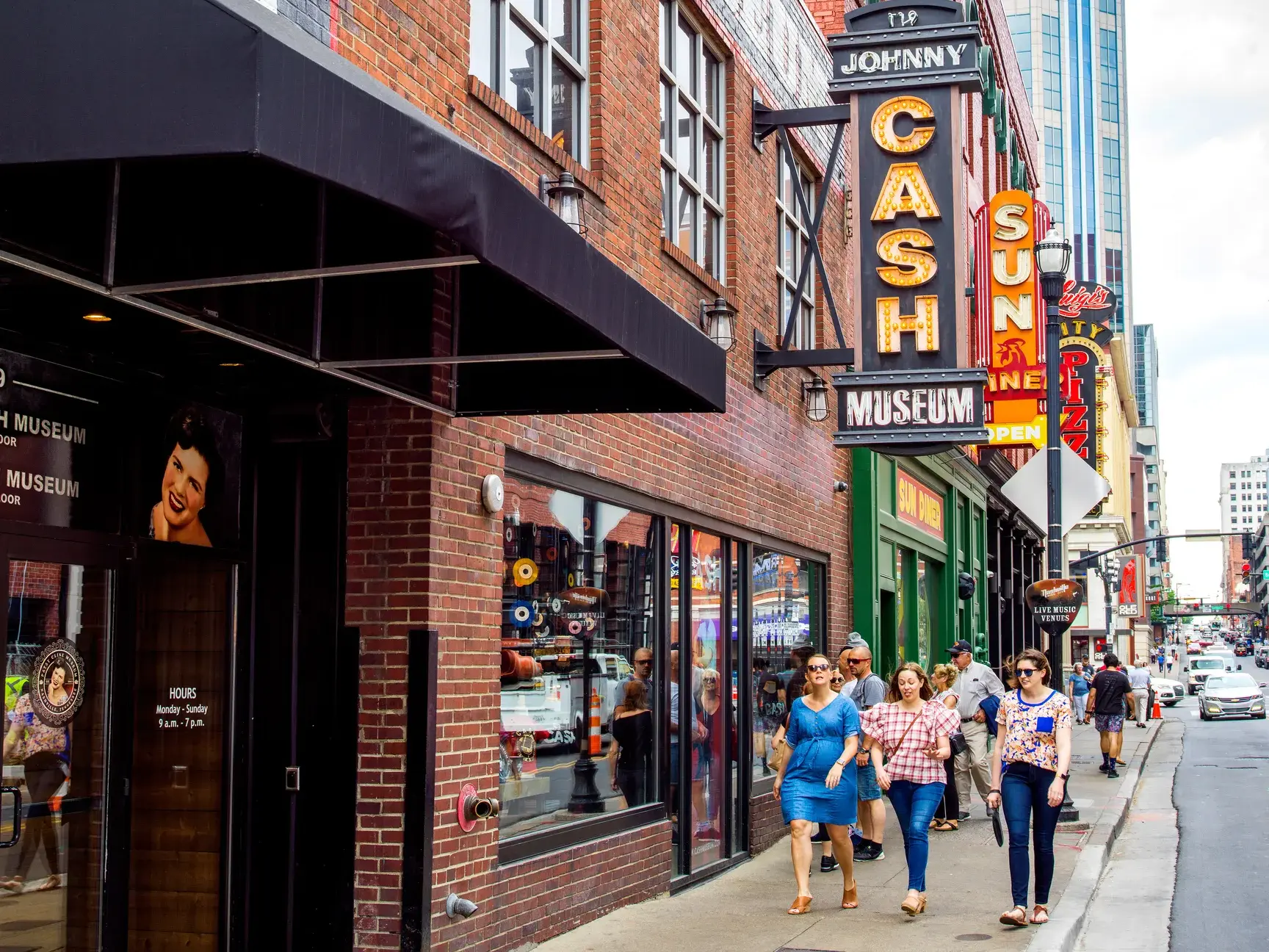 Eine kleine Gruppe von Besuchern spaziert tagsüber auf dem Gehweg vor dem Johnny Cash Museum in Nashville.