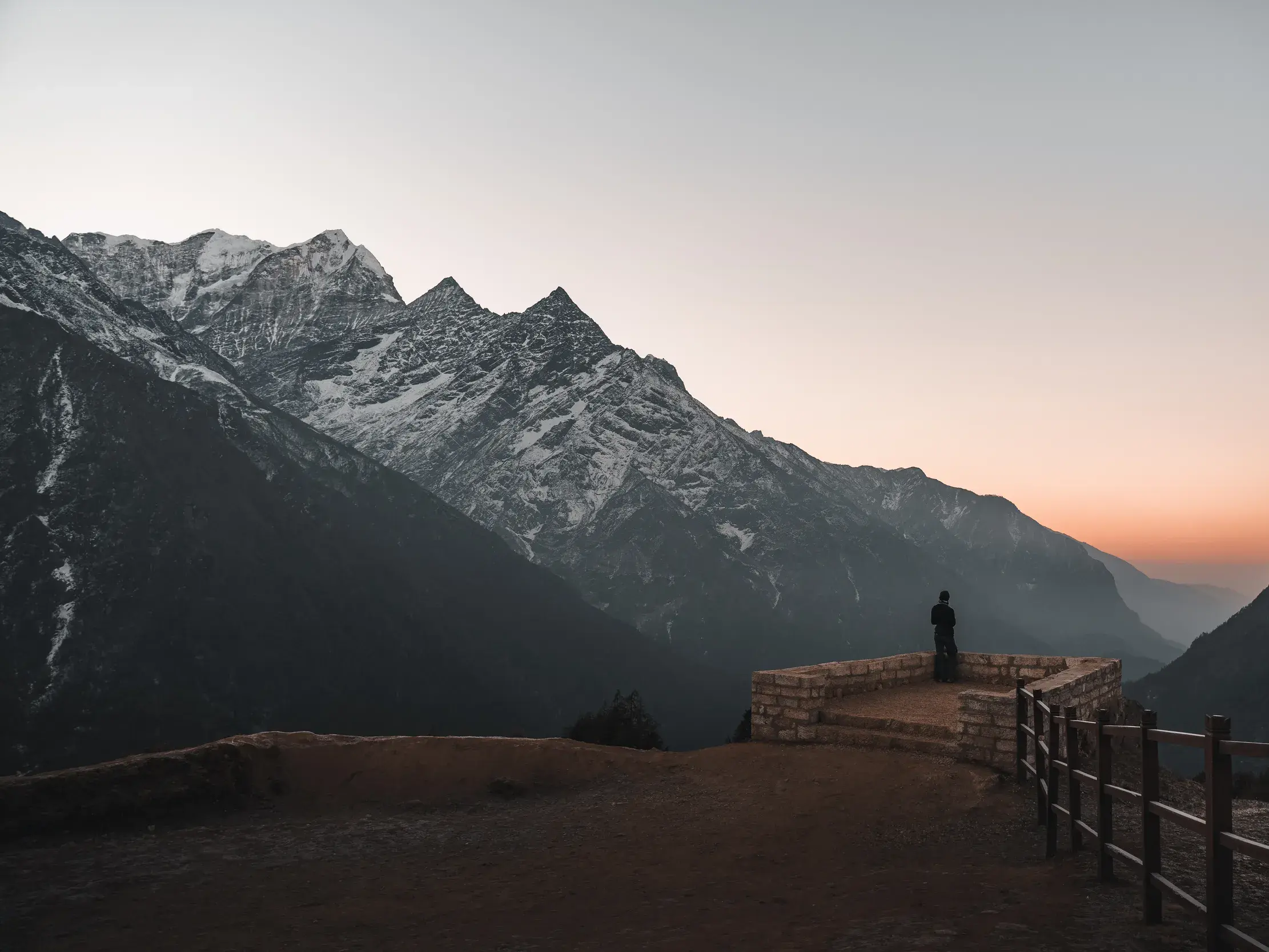 Ein Wanderer auf einem steinernen Aussichtspunkt in der Khumbu-Region genießt den Blick auf die schneebedeckten Himalaya-Gipfel.