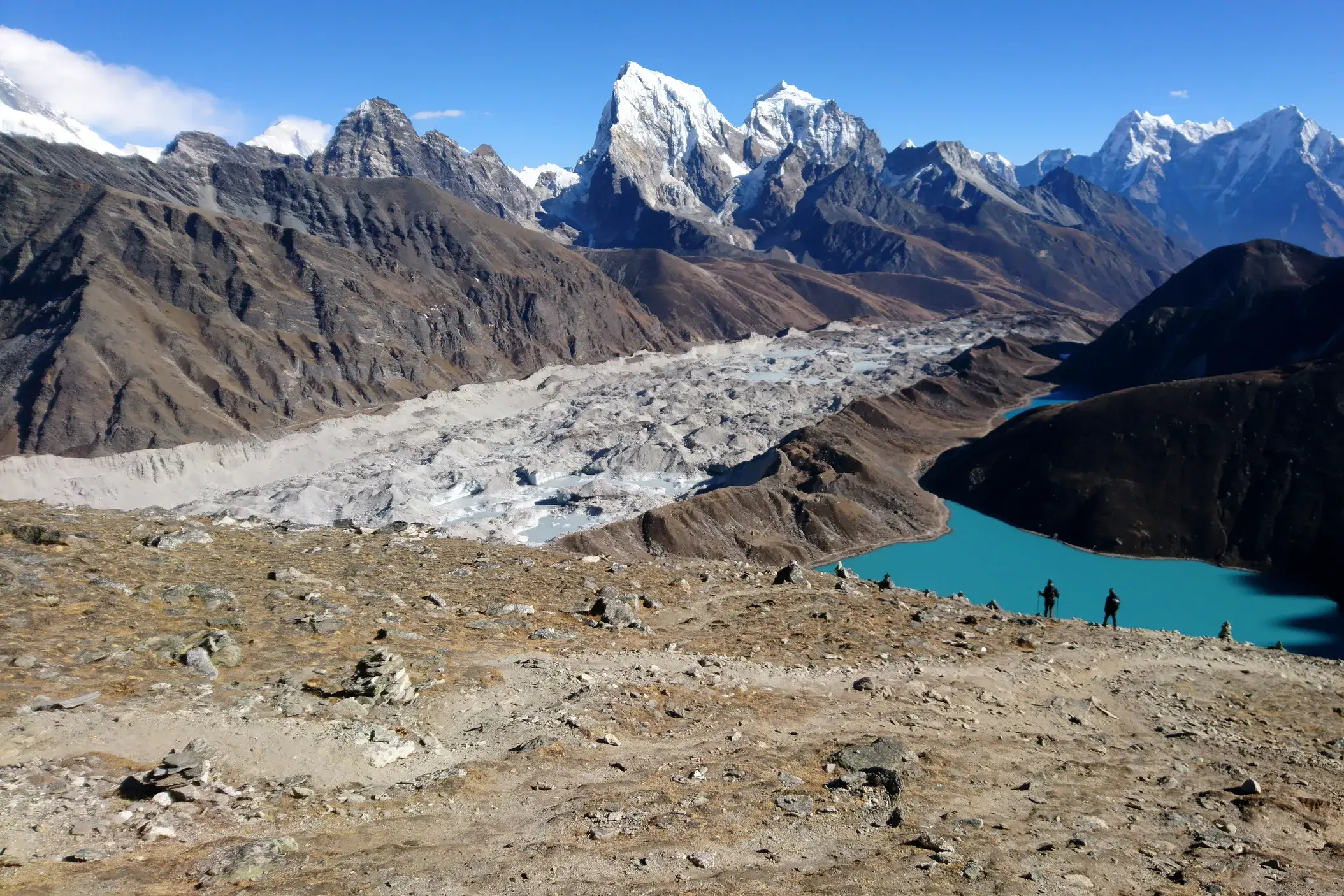 Trekking in Nepal: Wanderer blicken vom Renjo La Pass auf den türkisen Gokyo-See und den mächtigen Ngozumba-Gletscher.
