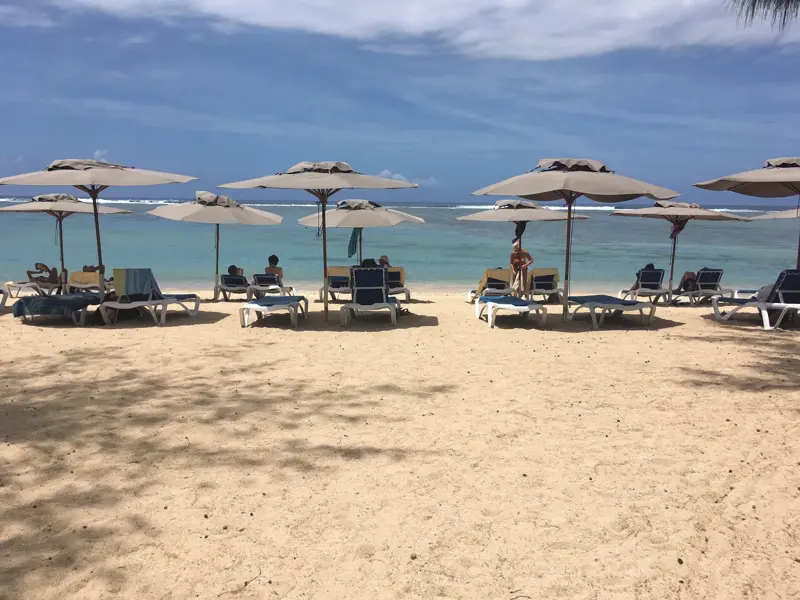 Sonnenschirme und Liegen am Sandstrand von La-Saline-les-Bains auf La Réunion, ideal zur Entspannung am Indischen Ozean.