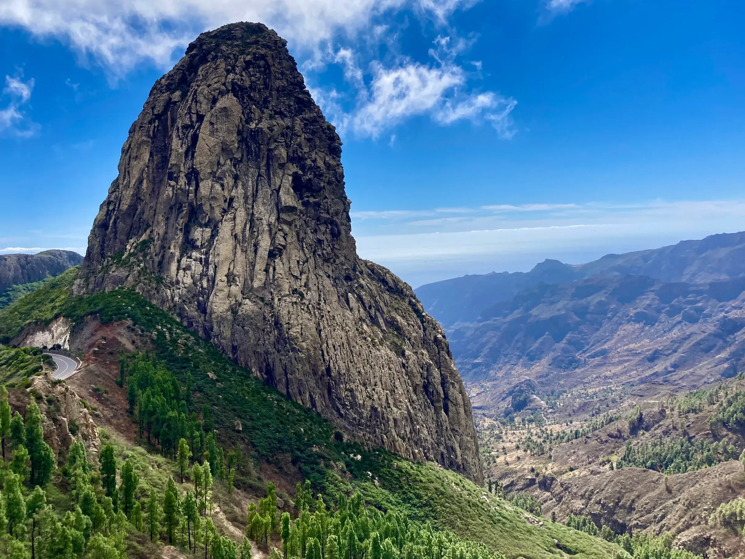 Majestätischer Vulkanschlot Roque de Agando auf La Gomera, umgeben von Kiefernwald und Blick in ein weites Bergtal.