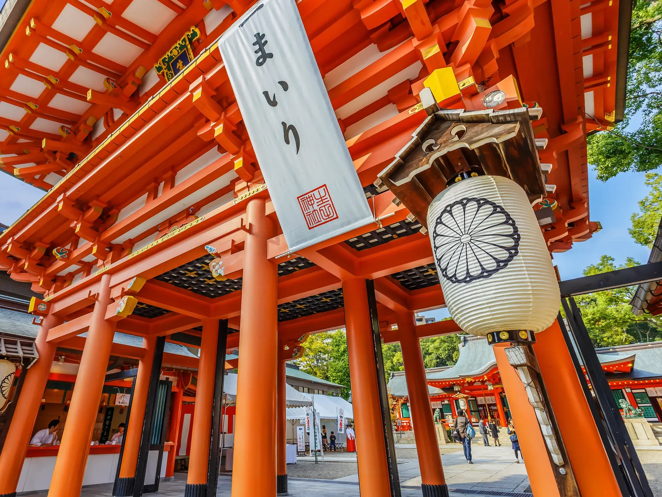 Froschperspektive des scharlachroten Eingangstors am Ikuta-Schrein in Kobe, geschmückt mit einer weißen Papierlaterne.
