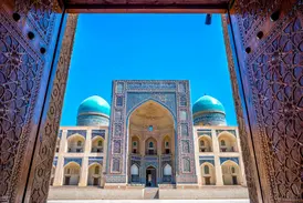 Geöffnete, reich verzierte Holztore geben den Blick frei auf die prachtvolle Mir-i-Arab-Medrese in Buchara, Usbekistan.