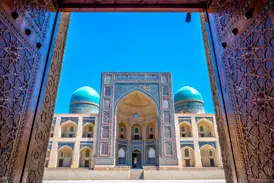 Geöffnete, reich verzierte Holztore geben den Blick frei auf die prachtvolle Mir-i-Arab-Medrese in Buchara, Usbekistan.