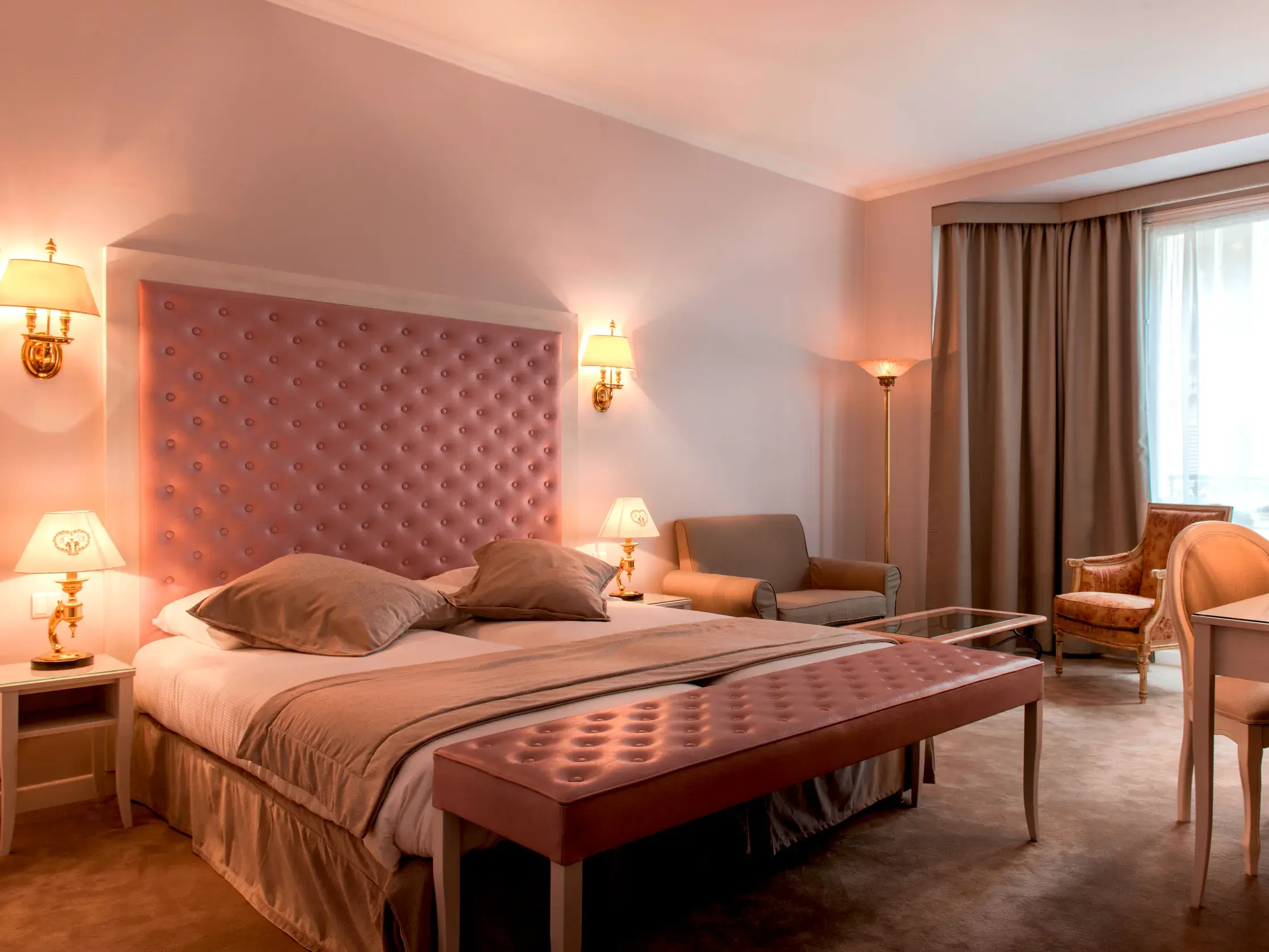 Einladendes Doppelzimmer im Hotel Princesse Caroline in Paris mit hohem, rosa gepolstertem Kopfteil und stilvoller Einrichtung.