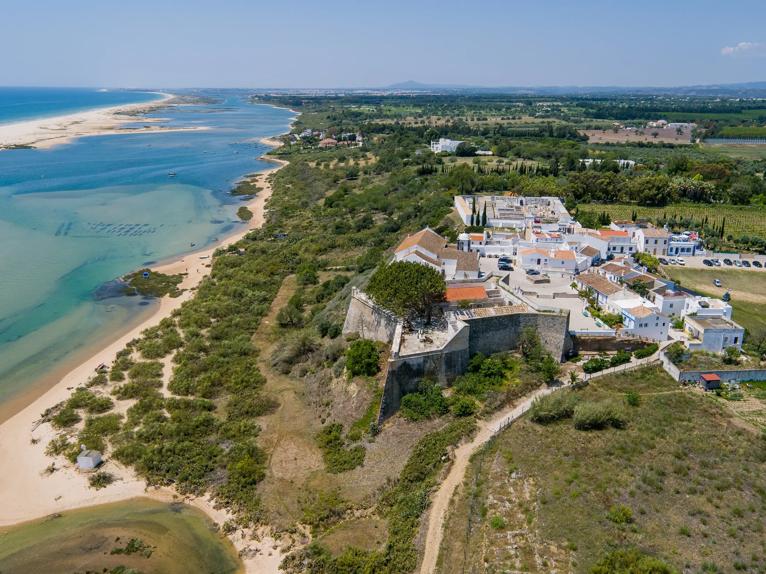 Weißes Dorf Cacela Velha auf einem Hügel an der Lagunenküste des Naturparks Ria Formosa an der Ostalgarve bei Sonnenschein.