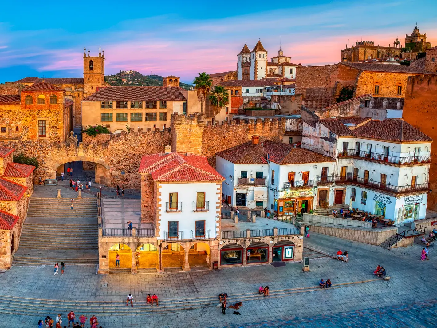 Die von der Abendsonne erleuchtete Plaza Mayor in Cáceres mit Blick auf die historische Altstadt und ihre Stadtmauer.