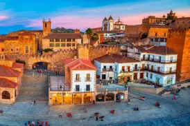 Die von der Abendsonne erleuchtete Plaza Mayor in Cáceres mit Blick auf die historische Altstadt und ihre Stadtmauer.