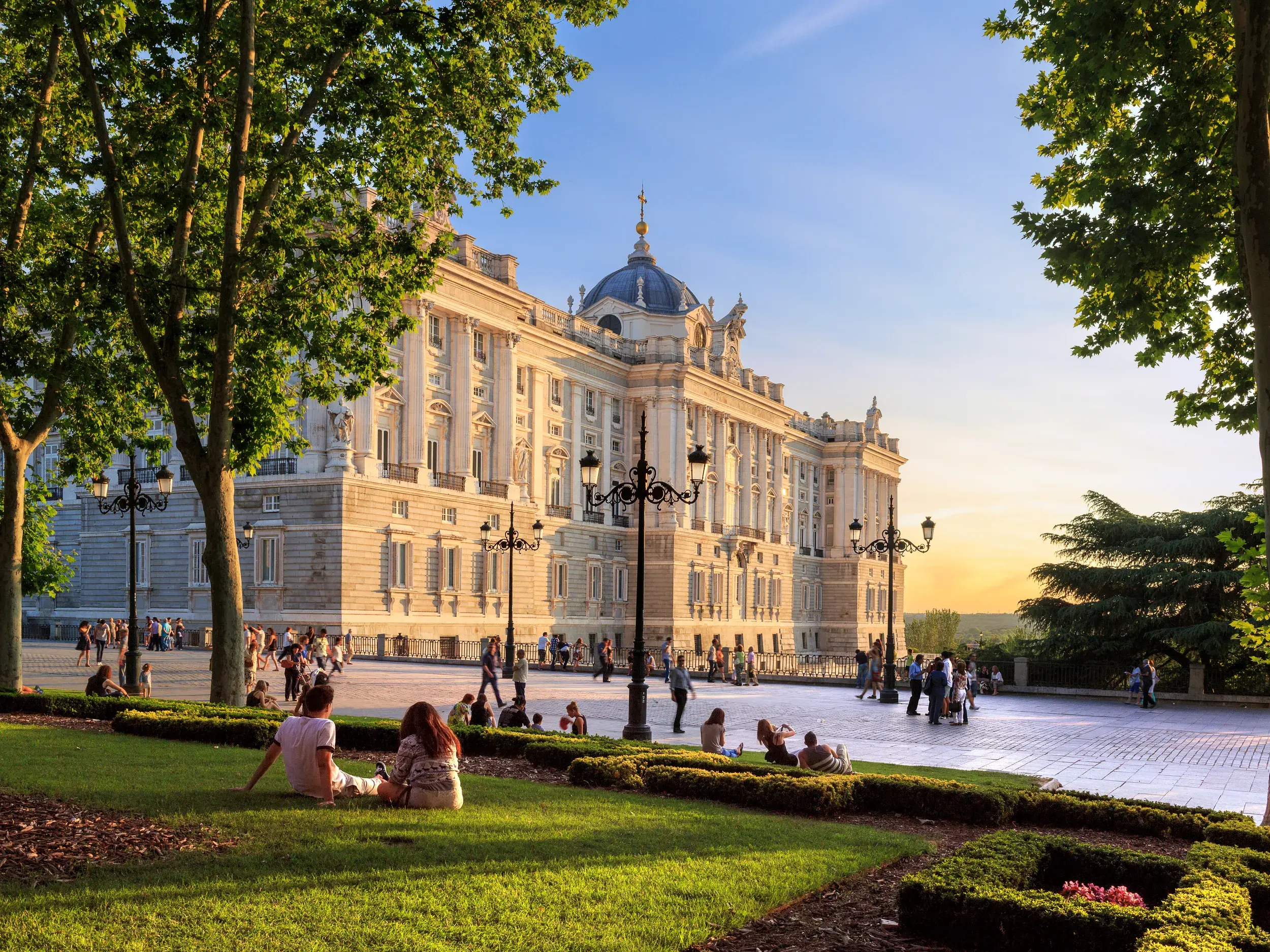 Besucher genießen die Abendsonne vor dem prachtvollen Königspalast von Madrid auf einer Studienreise durch Kastilien.