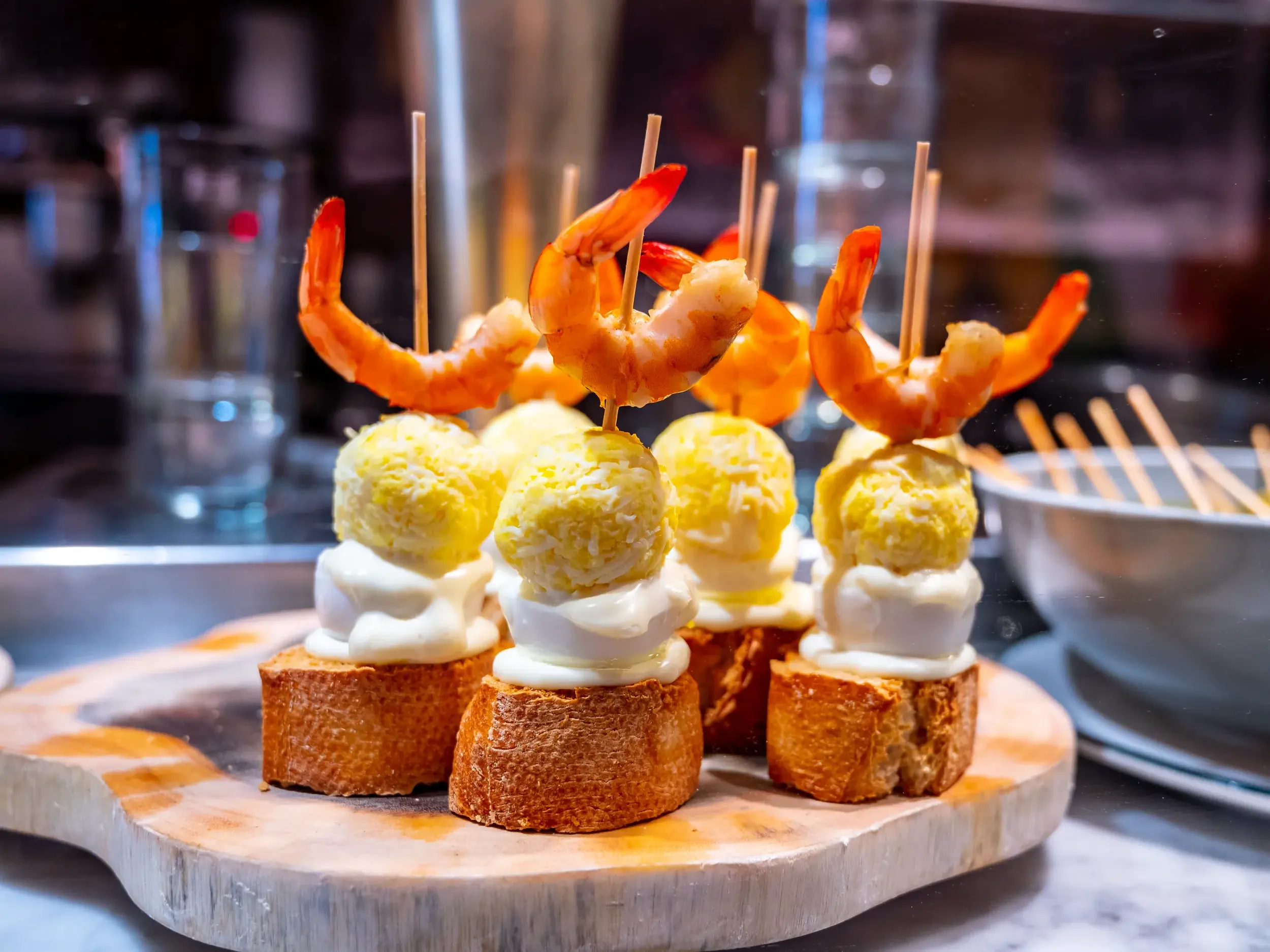 Typisch baskische Pintxos mit Garnelen, kunstvoll aufgespießt und auf einem Holzbrett in einer Bar in Bilbao serviert.