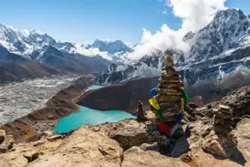 Steinmännchen mit Gebetsfahnen auf dem Gokyo Ri mit Blick auf den türkisen Gokyo-See und das gewaltige Himalaya-Panorama in Nepal.