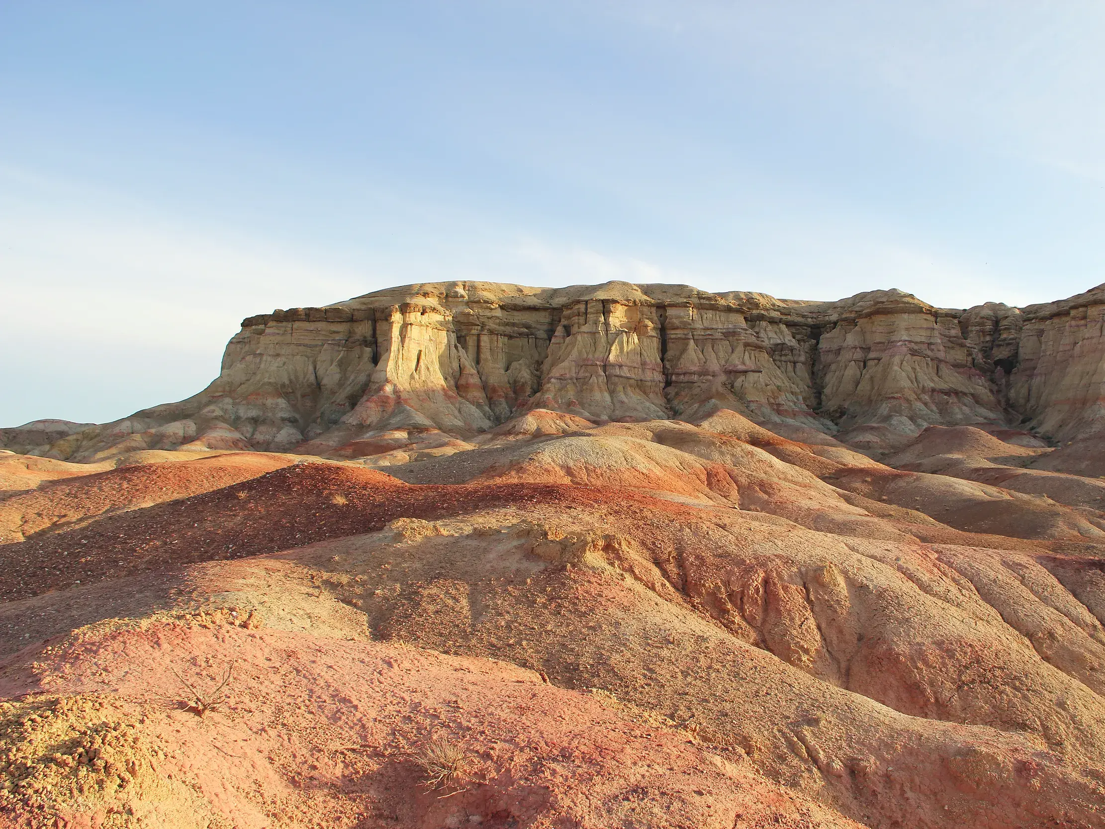 Bizarre, rot leuchtende Felslandschaft der glühenden Klippen von Bayanzag während einer Wanderreise in der Wüste Gobi.