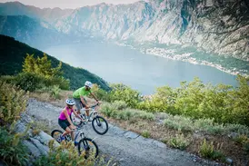 Ein Paar auf Mountainbikes auf einem Höhenweg mit Panoramablick über die fjordartige Bucht von Kotor in Montenegro.