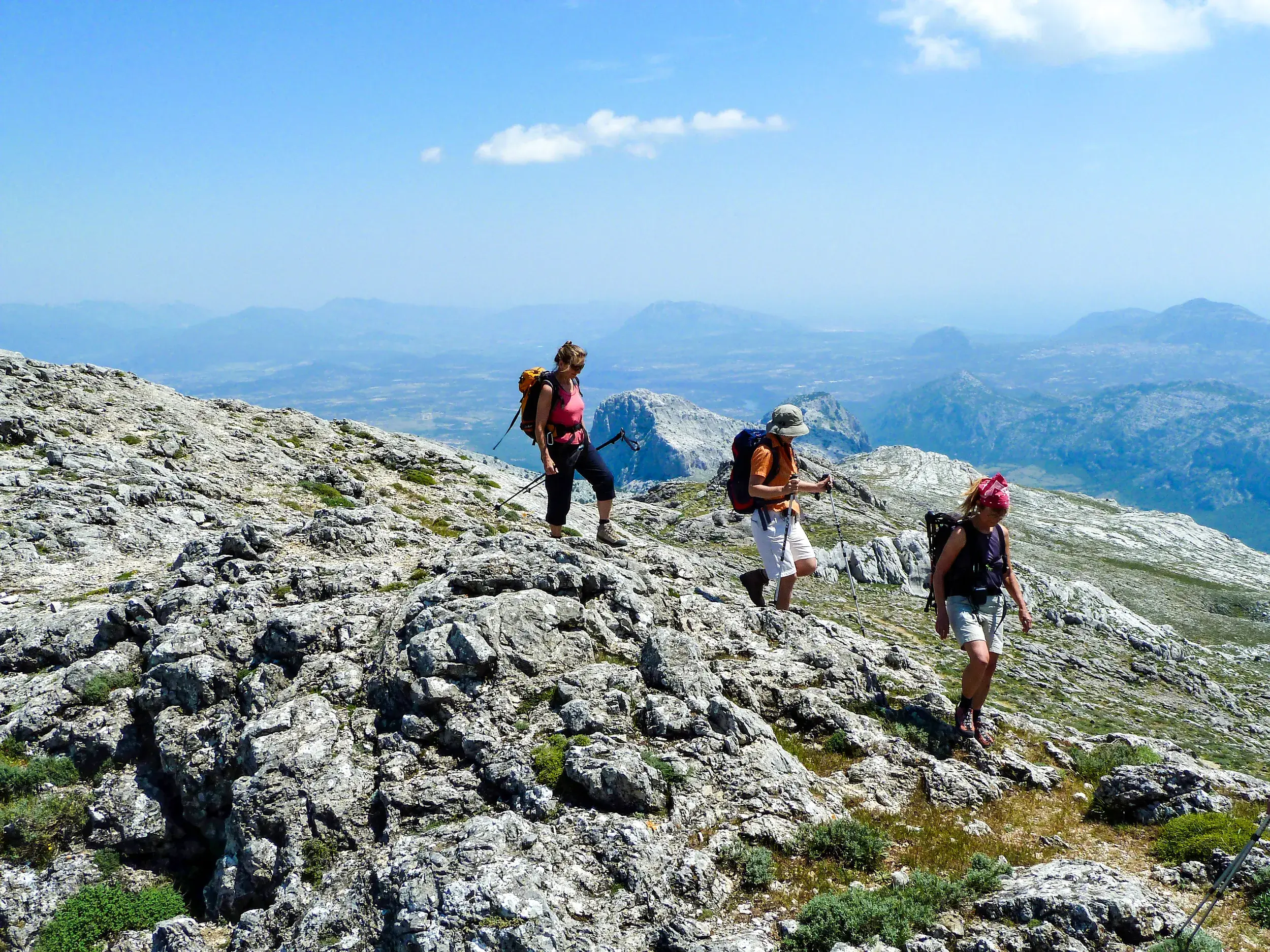 Eine kleine Wandergruppe auf dem felsigen Gipfel des Monte Corrasi mit weitem Panoramablick über das Supramonte-Gebirge.