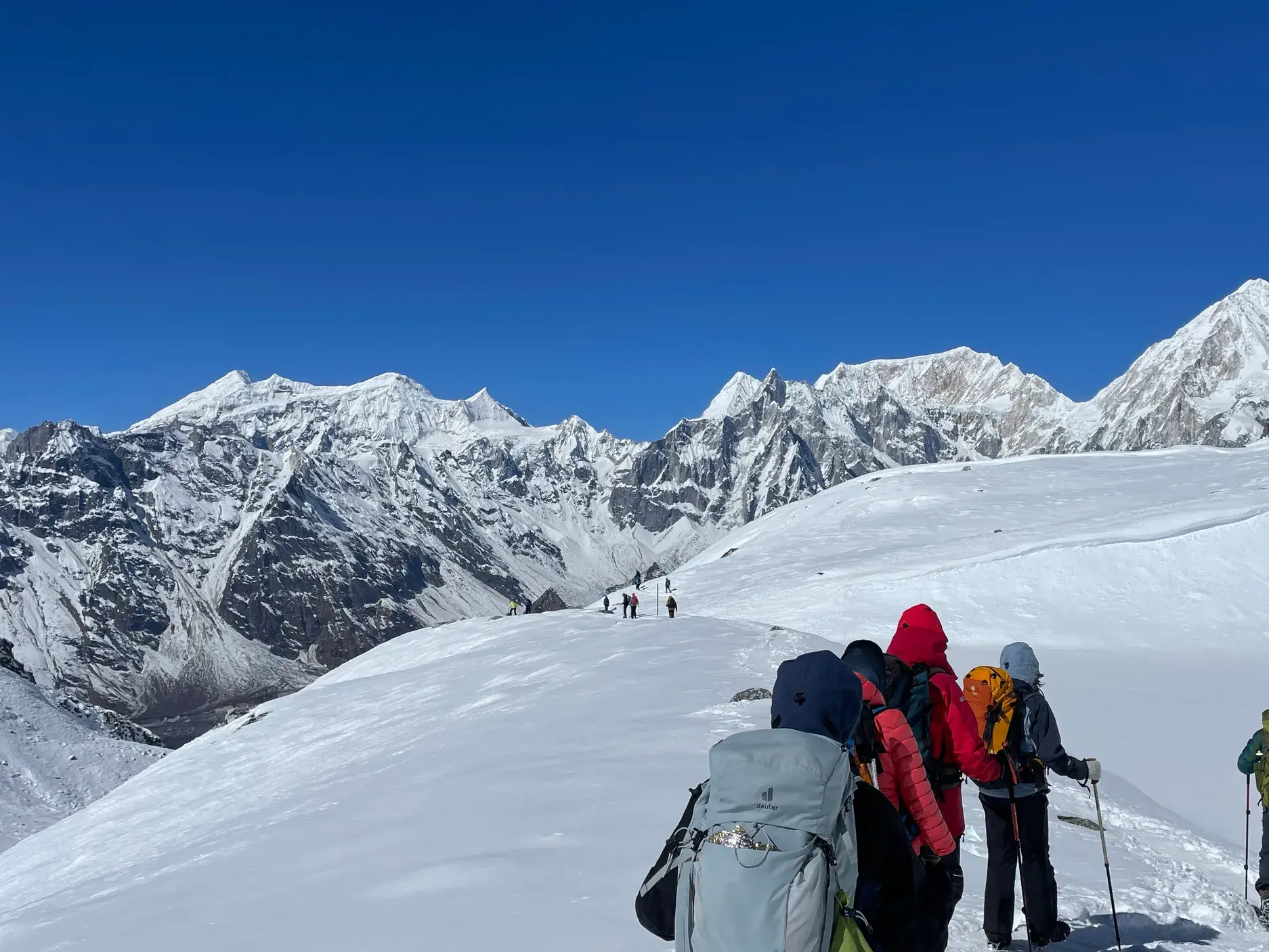 Eine Trekkinggruppe wandert auf dem schneebedeckten Larkya-Pass mit Panoramablick auf die Gipfel des Himalaya in Nepal.