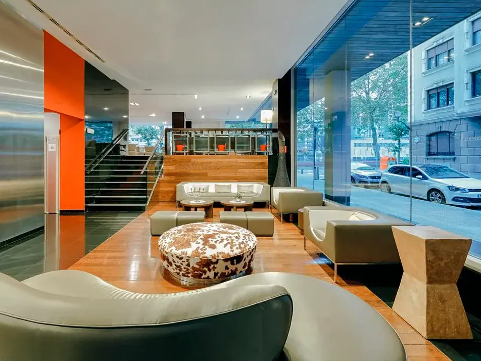 Die moderne Lobby des Hotel Hesperia Bilbao mit stilvollen Sitzmöbeln, Holzboden und großer Fensterfront zur Straße.