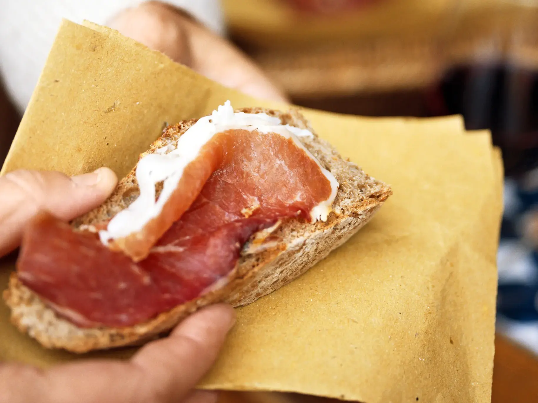 Nahaufnahme von Prosciutto di San Daniele auf einer Scheibe Brot bei einer Schinkenverkostung während einer Studienreise in Friaul.