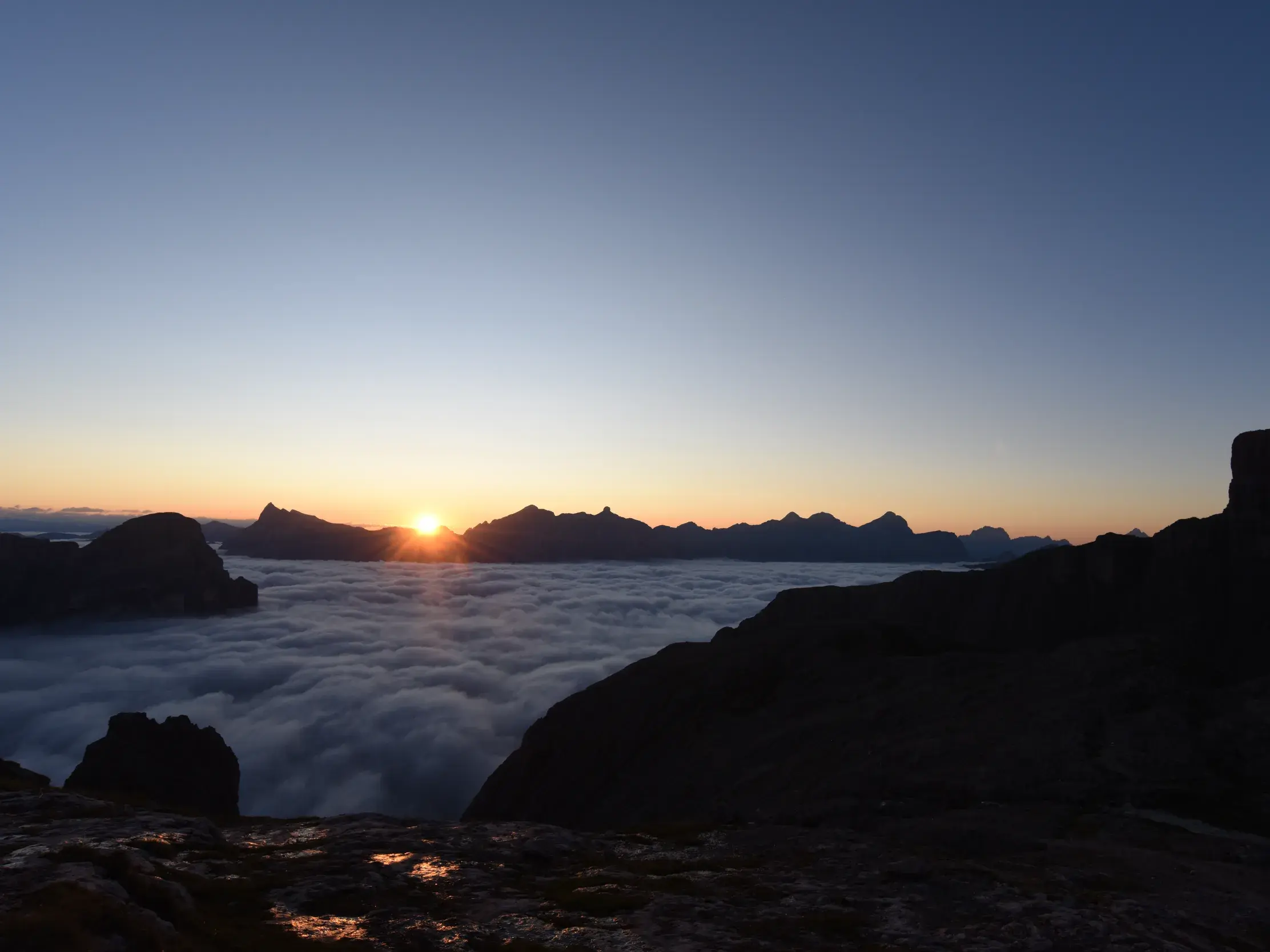 Eindrucksvoller Sonnenaufgang auf der Oberbachernspitze mit Blick auf ein Wolkenmeer und die Gipfel der Dolomiten.