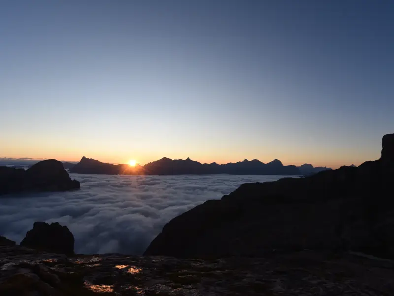 Eindrucksvoller Sonnenaufgang auf der Oberbachernspitze mit Blick auf ein Wolkenmeer und die Gipfel der Dolomiten.