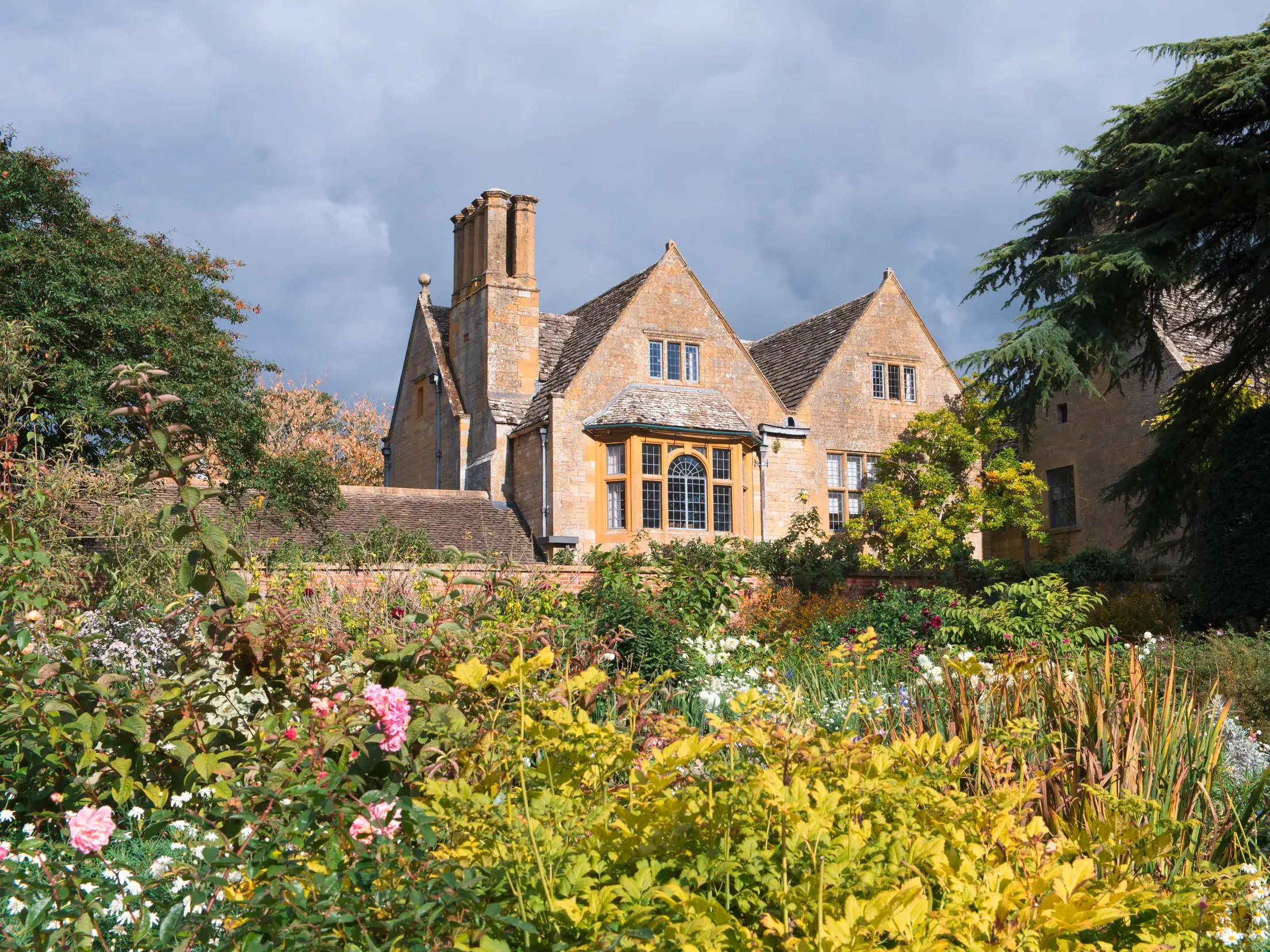 Üppiger Blumengarten vor dem historischen Herrenhaus des Hidcote Garden, ein Juwel der Gartenkunst in den Cotswolds.
