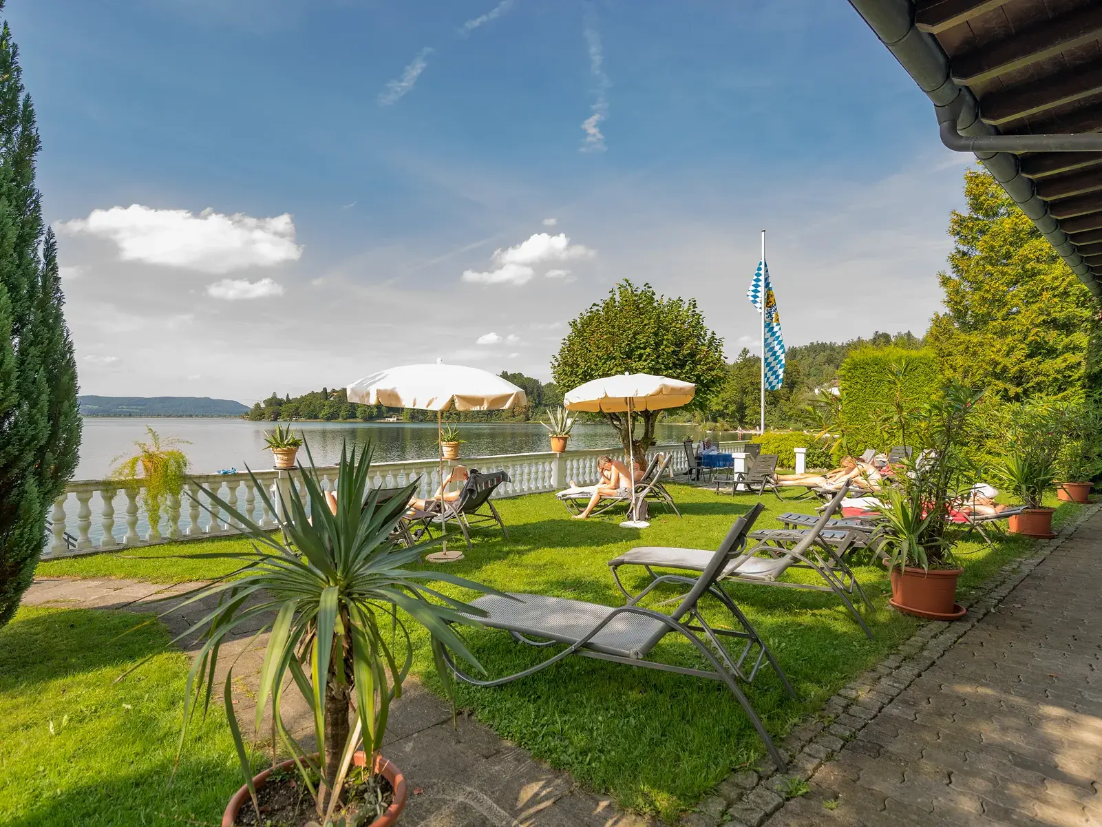Entspannung nach der Wanderung: Gäste relaxen auf der Liegewiese des Seehotels Grauer Bär direkt am Ufer des Kochelsees.