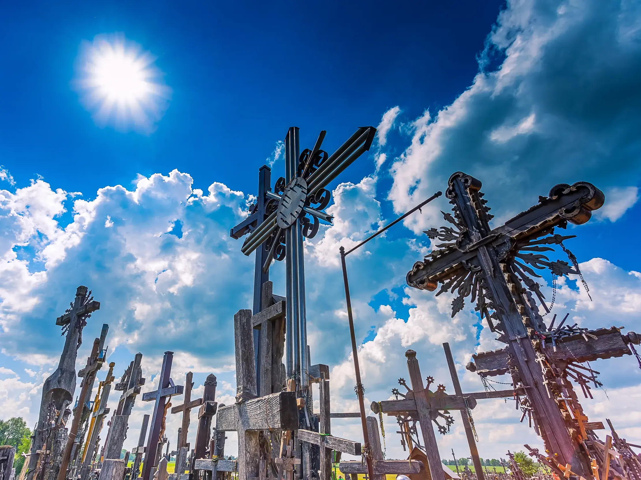Zahlreiche Kreuze am Nationalheiligtum Berg der Kreuze in Siauliai, Litauen, ragen in den blauen Himmel mit strahlender Sonne.