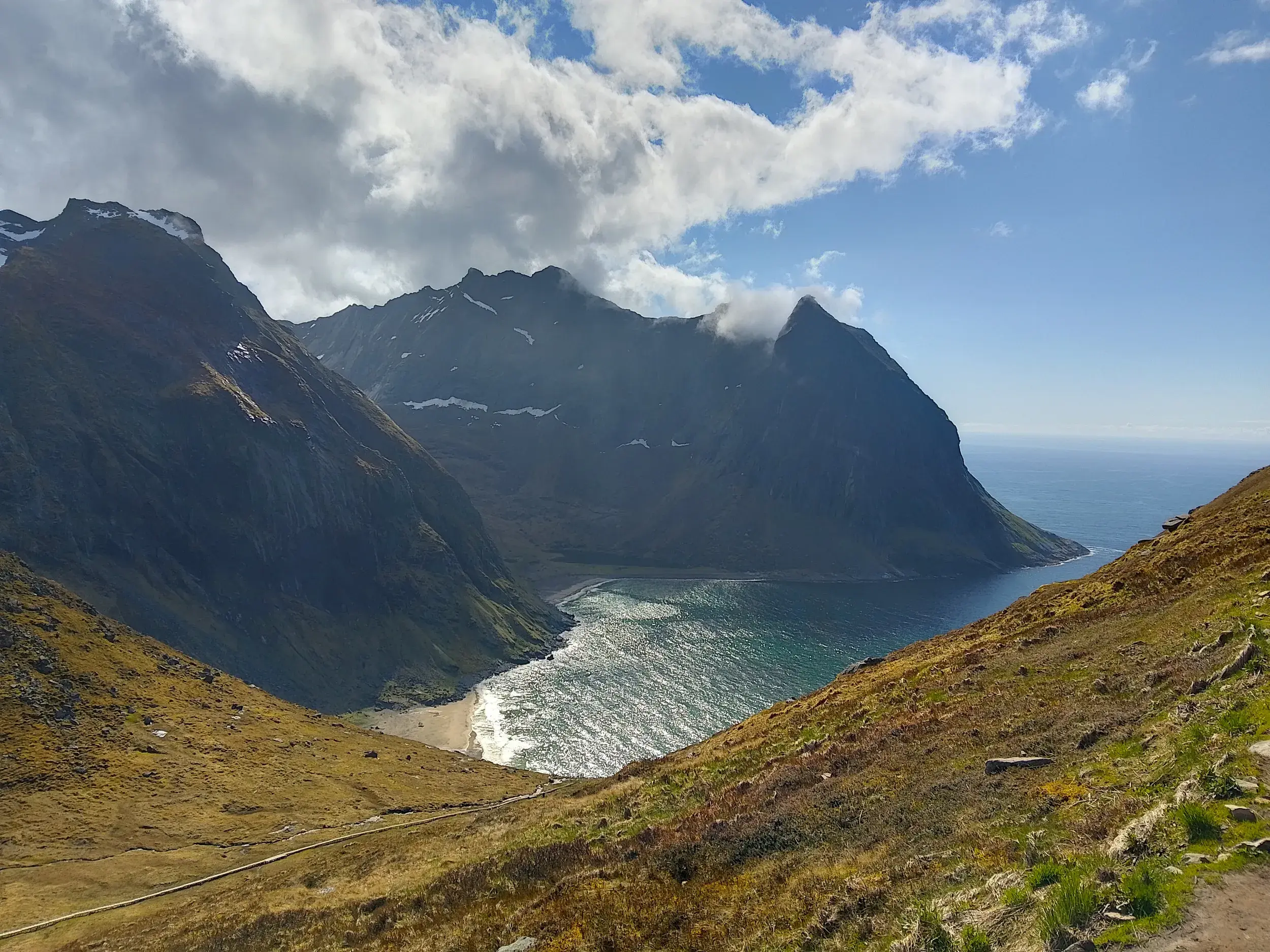 Aussicht beim Wandern vom Berg Ryten auf die Kvalvika-Bucht auf den Lofoten, umgeben von steilen, felsigen Gipfeln.